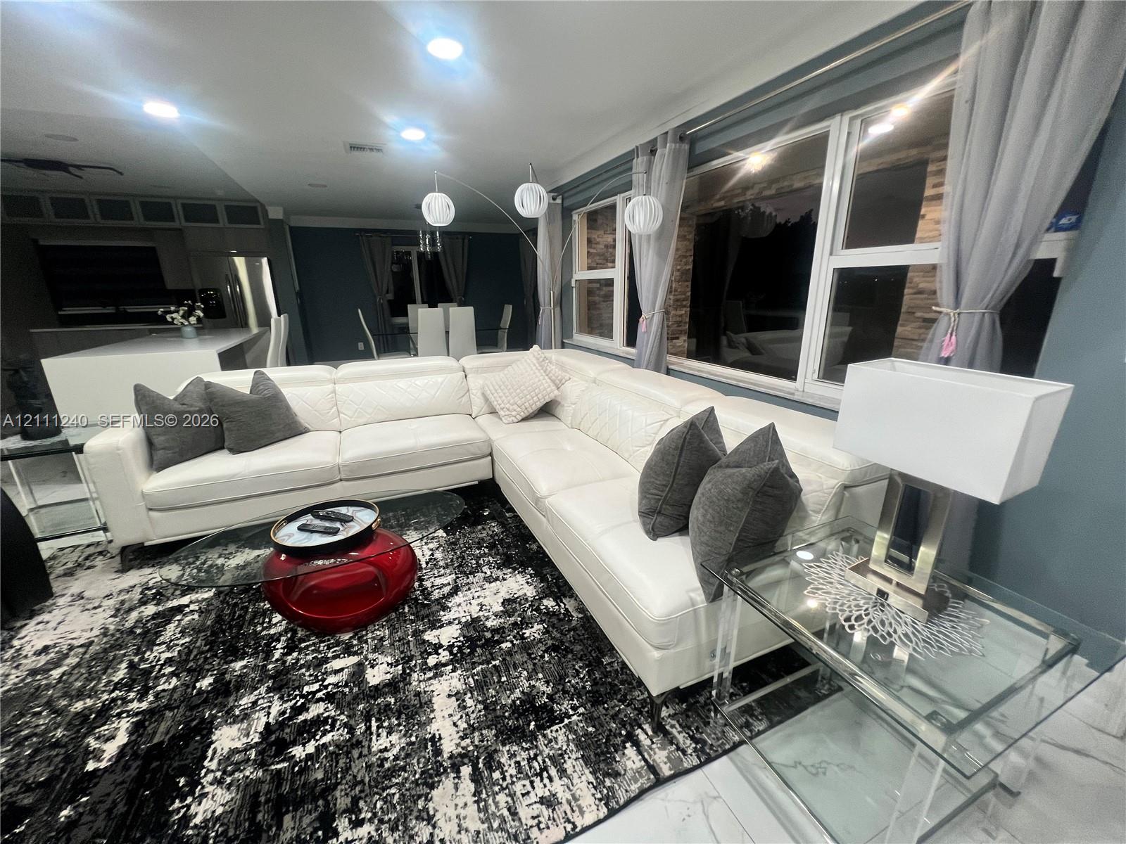 Open-concept interior featuring large-format polished tile flooring, recessed ceiling lighting, and expansive windows with custom stone-finish trim