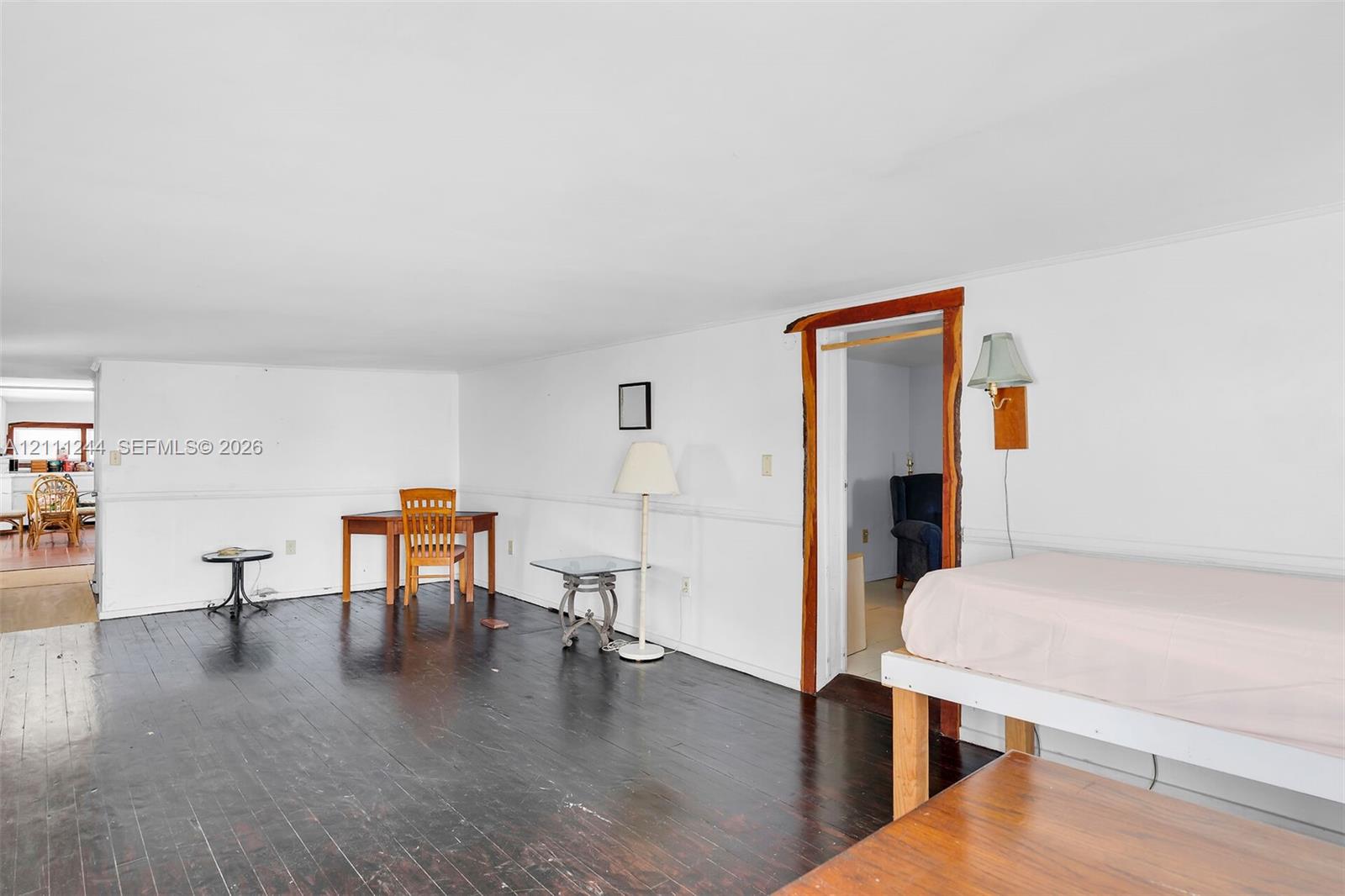 Interior space featuring dark-stained wood-finish flooring, white wall wainscoting, and a doorway framed with natural live-edge wood trim