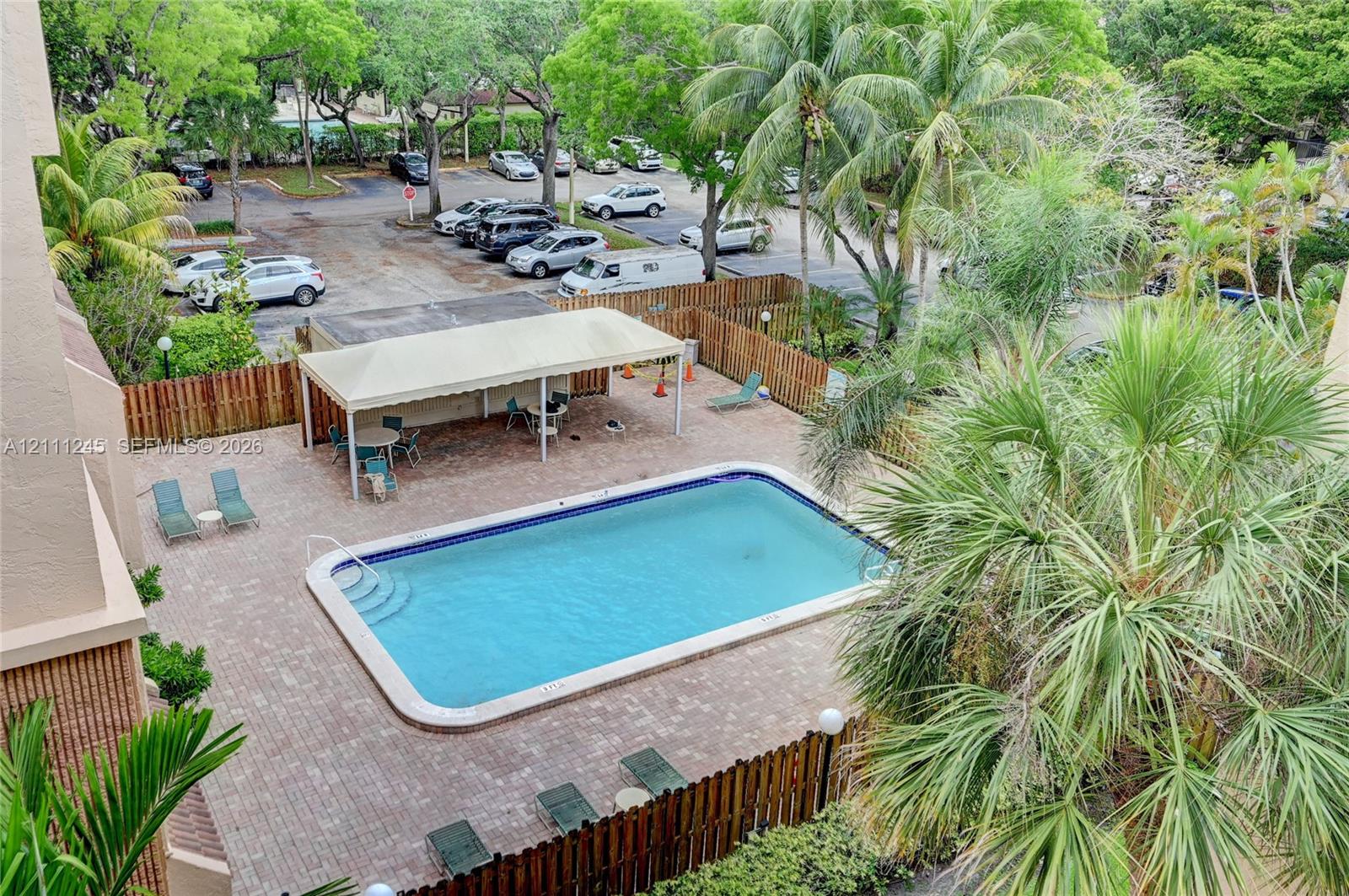 Swimming pool with concrete pavers, covered pergola, and surrounding perimeter wood fencing Swimming pool with concrete pavers, covered pergola, and surrounding perimeter wood fencing