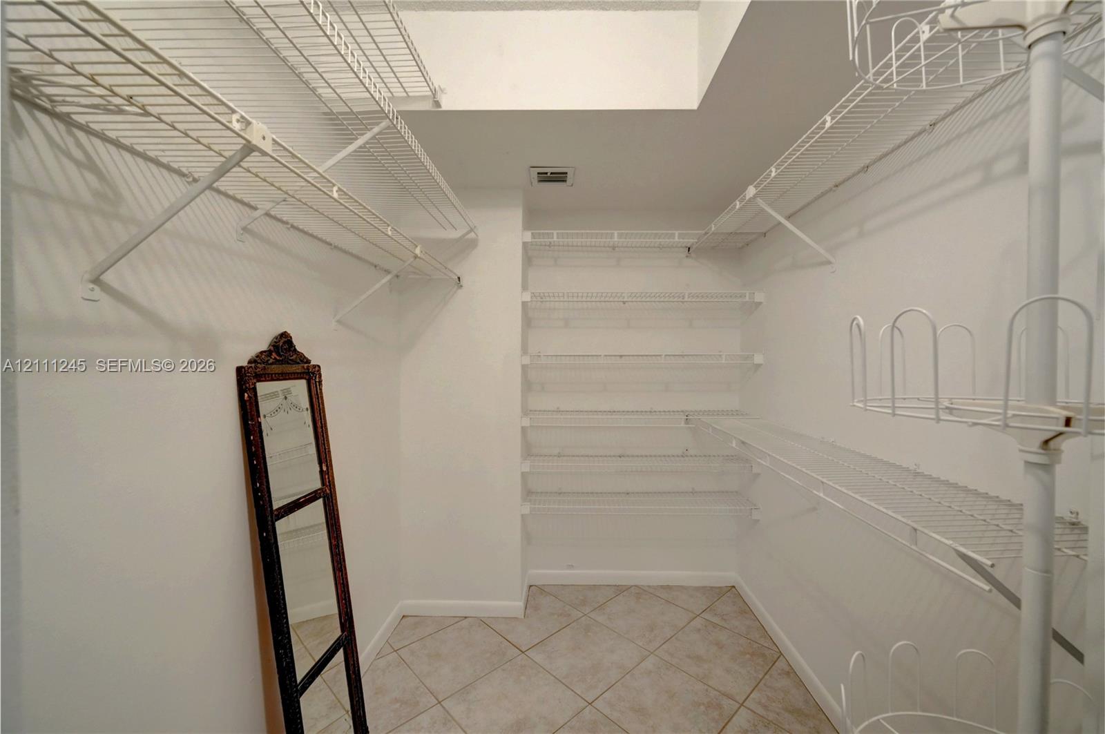 Walk-in storage space featuring ceramic tile flooring and multi-level white wire shelving