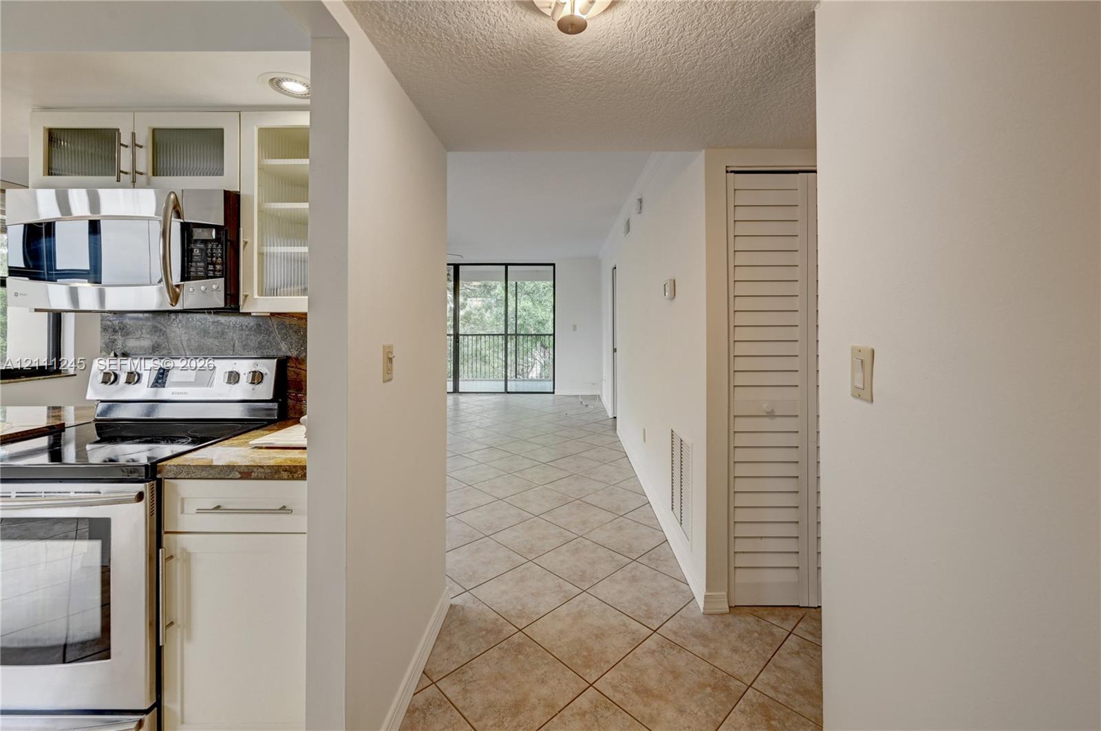 Kitchen featuring stainless steel appliances, white cabinetry, stone-finish countertops, and tile flooring Kitchen featuring stainless steel appliances, white cabinetry, stone-finish countertops, and tile flooring