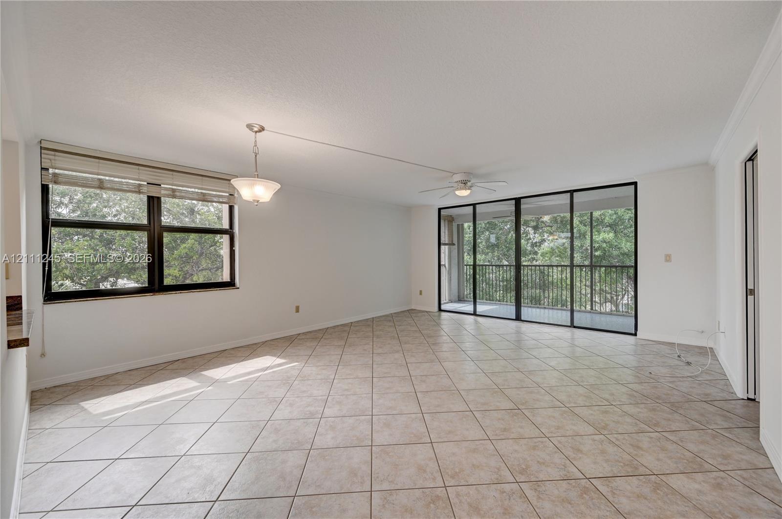 Neutral ceramic tile flooring, floor-to-ceiling sliding glass doors, integrated ceiling fan, and pendant lighting