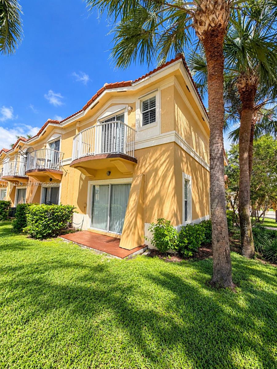 Multi-story exterior featuring stucco siding, a tiled roof, second-level balconies with metal railings, sliding glass doors, and a ground-level patio Multi-story exterior featuring stucco siding, a tiled roof, second-level balconies with metal railings, sliding glass doors, and a ground-level patio