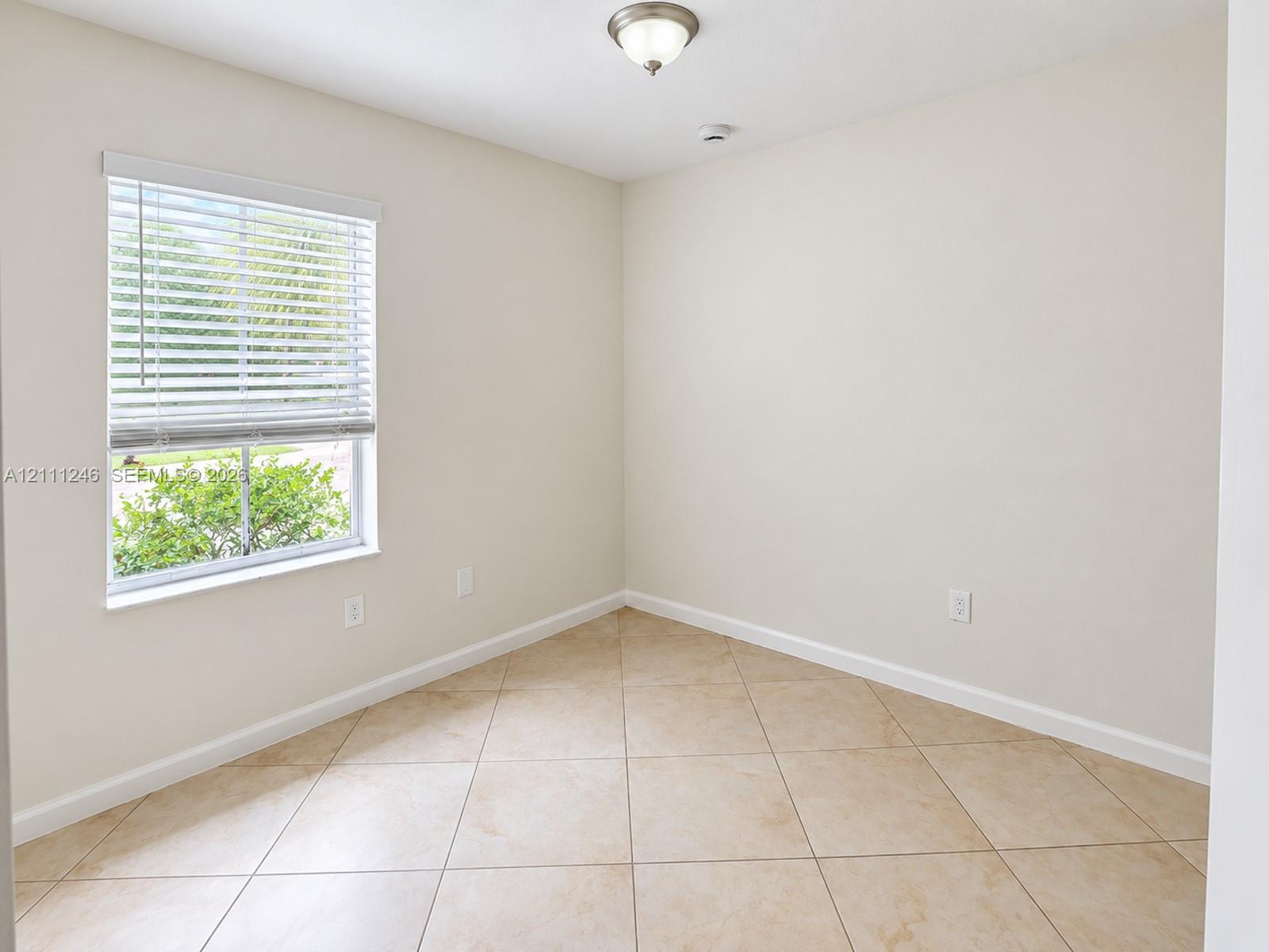 Neutral wall tones, diagonal-laid tile flooring, and a single-hung window with white horizontal blinds