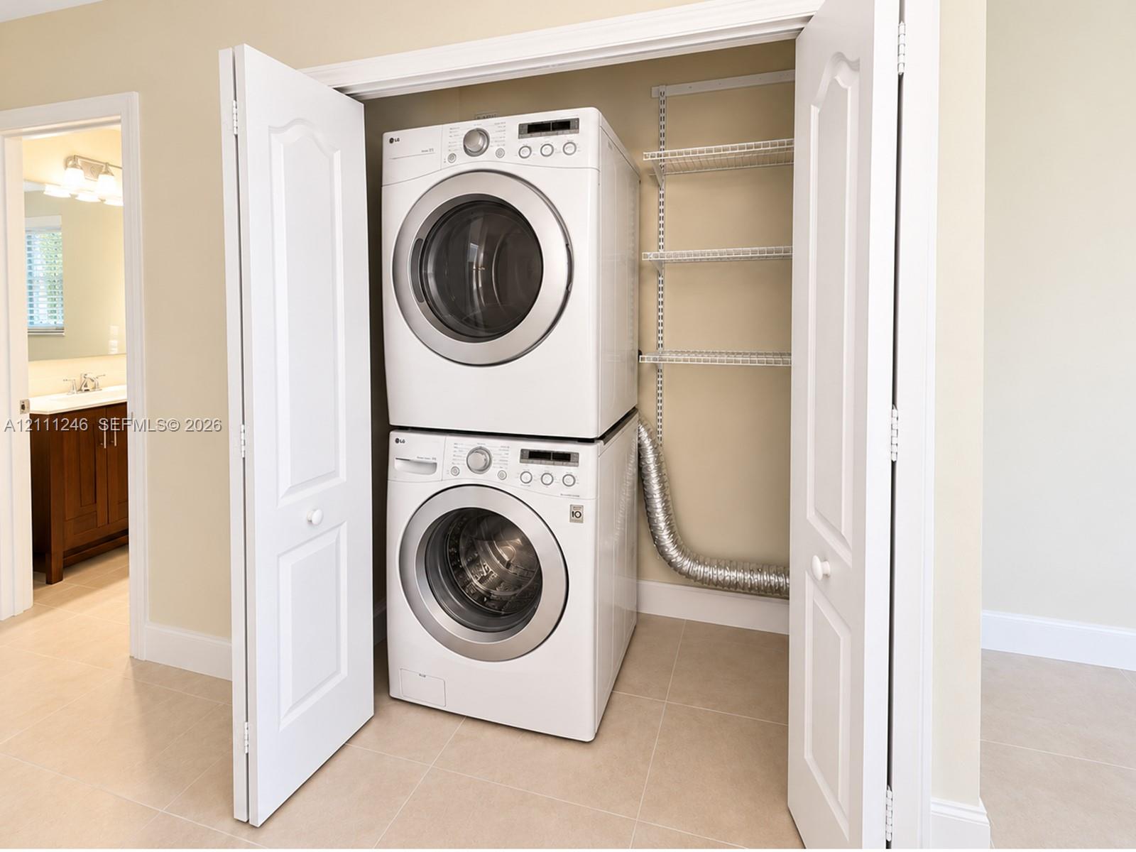 Dedicated laundry closet featuring a stacked washer and dryer, adjustable wire shelving, and bi-fold doors