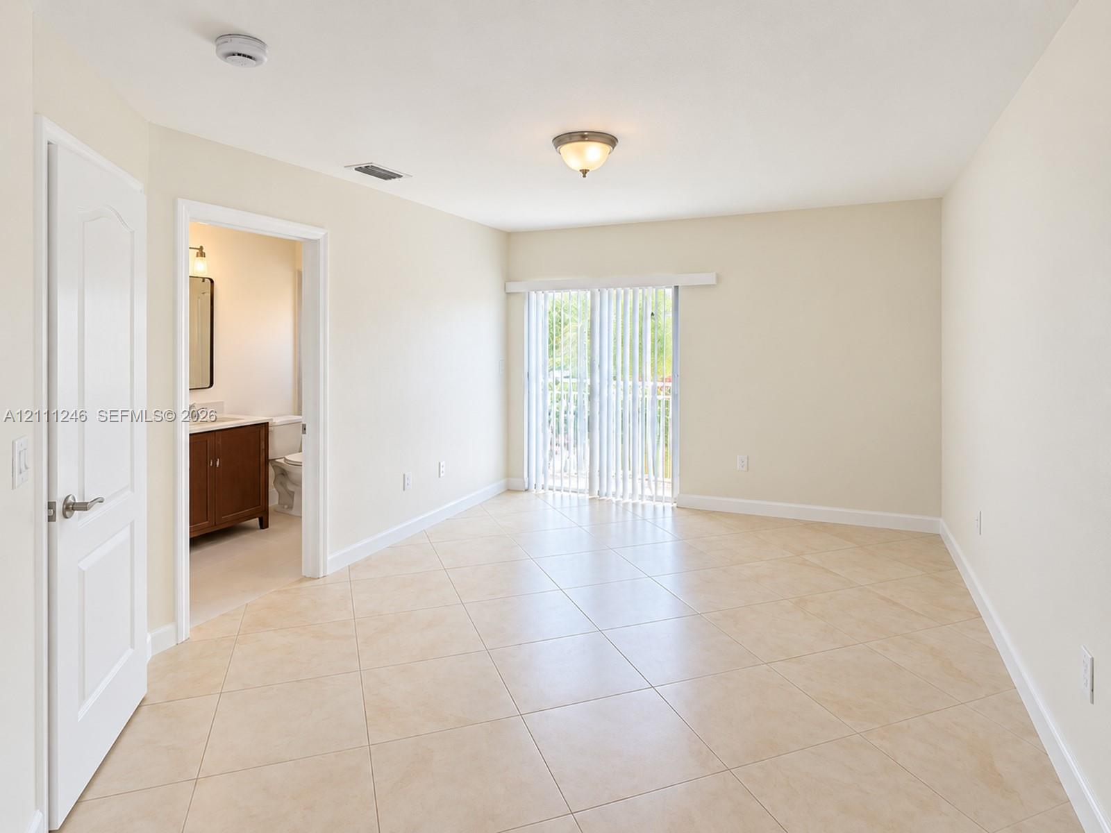 Neutral-toned tile flooring, sliding glass doors with vertical blinds, and a built-in flush-mount light fixture