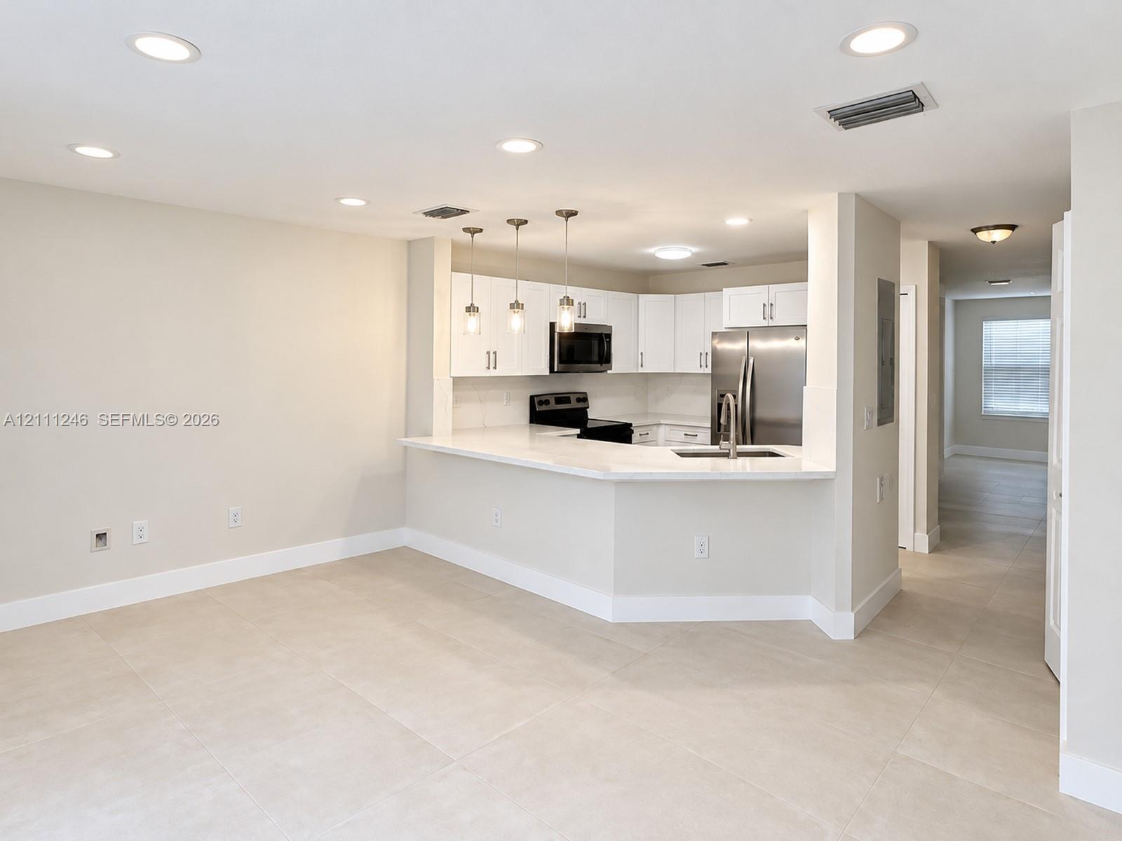 Kitchen featuring white cabinetry, solid-surface countertops, stainless steel appliances, a breakfast bar, and recessed lighting Kitchen featuring white cabinetry, solid-surface countertops, stainless steel appliances, a breakfast bar, and recessed lighting