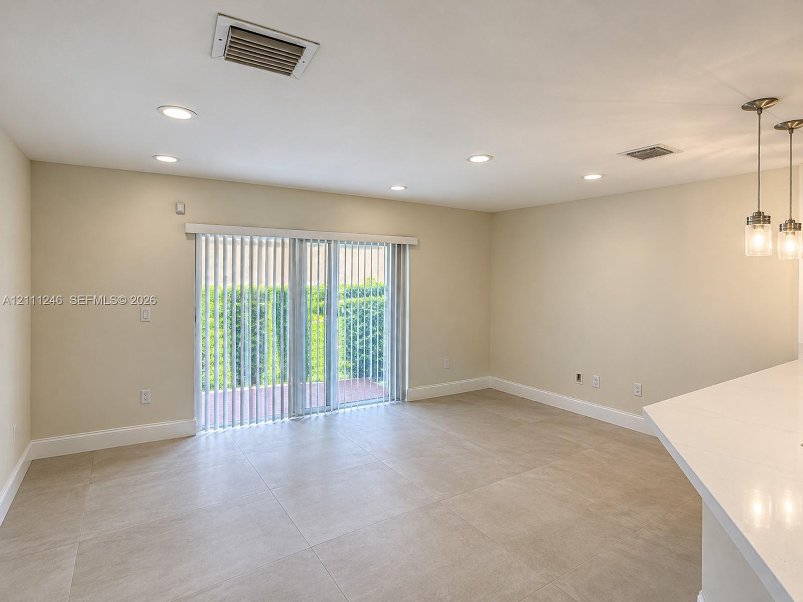 Large-format tile flooring, recessed ceiling lighting, sliding glass doors, and dual pendant light fixtures Large-format tile flooring, recessed ceiling lighting, sliding glass doors, and dual pendant light fixtures