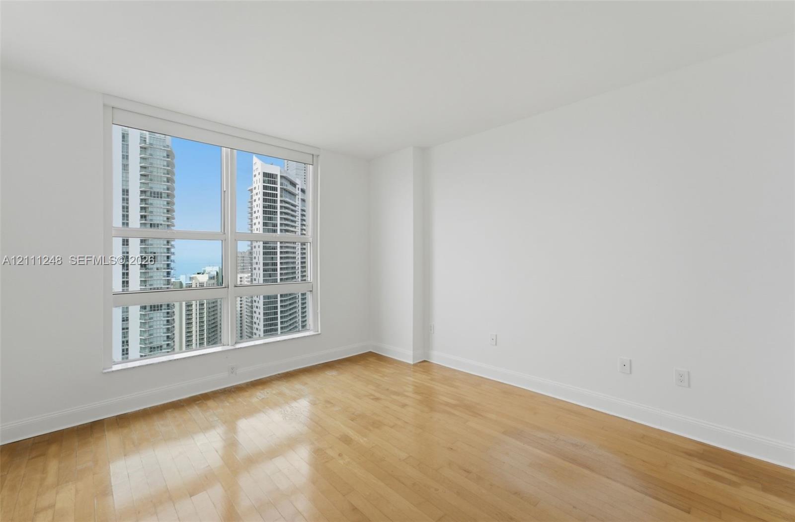 Floor-to-ceiling window featuring urban surroundings, wood-finish flooring, and crisp white wall finishes
