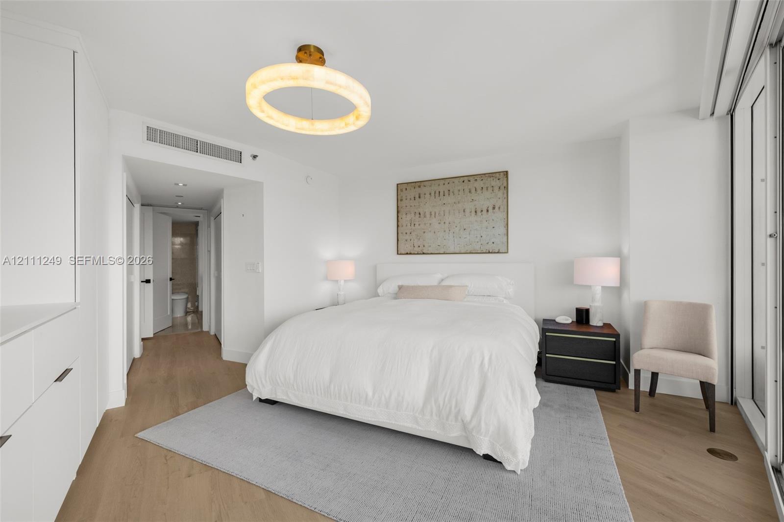 Wood-finish flooring, custom built-in cabinetry, and a circular geometric chandelier