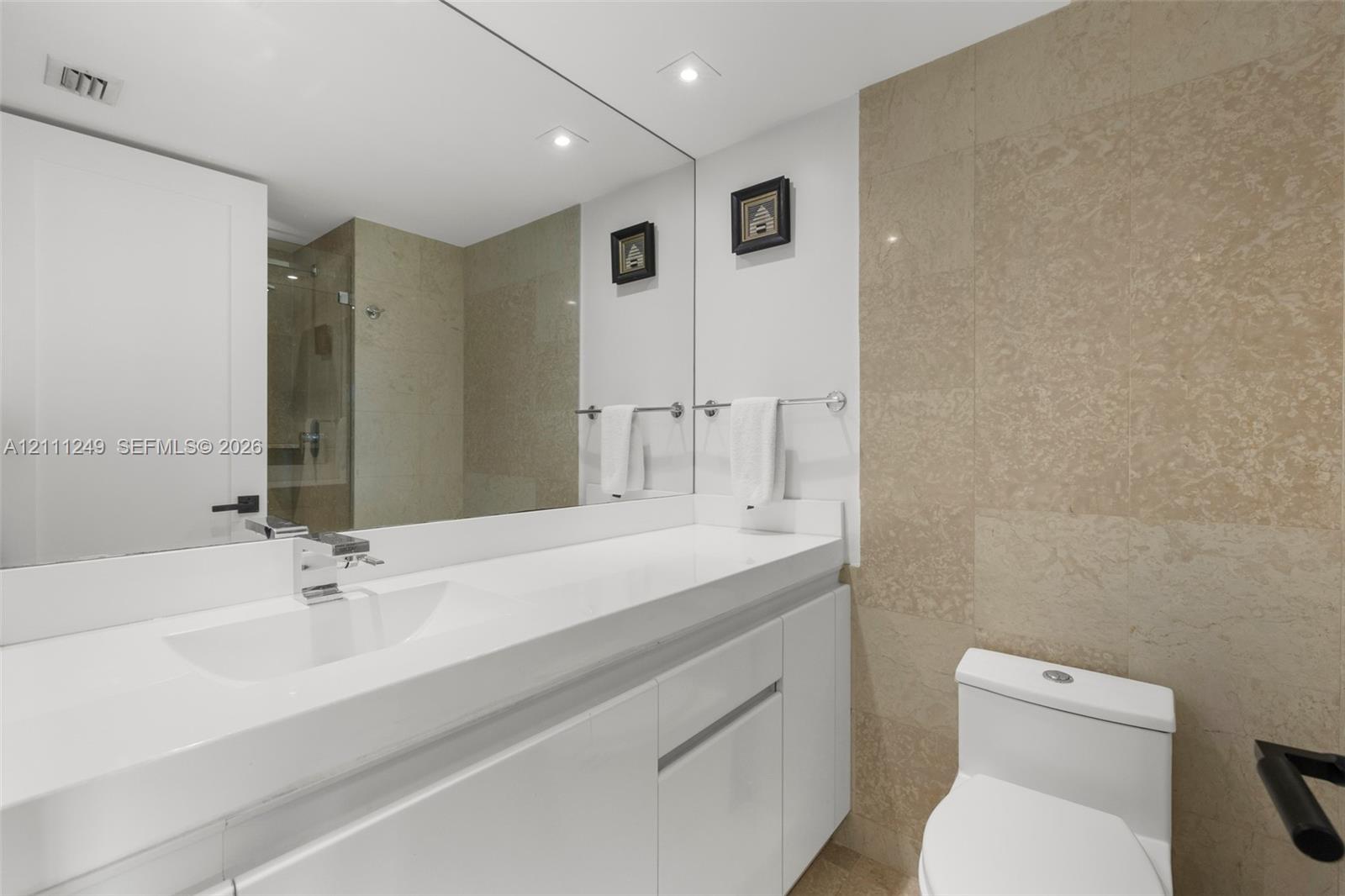 Walk-in shower featuring a glass enclosure, rainfall showerhead, wall-mounted control valve, and stone-finish wall tile Walk-in shower featuring a glass enclosure, rainfall showerhead, wall-mounted control valve, and stone-finish wall tile
