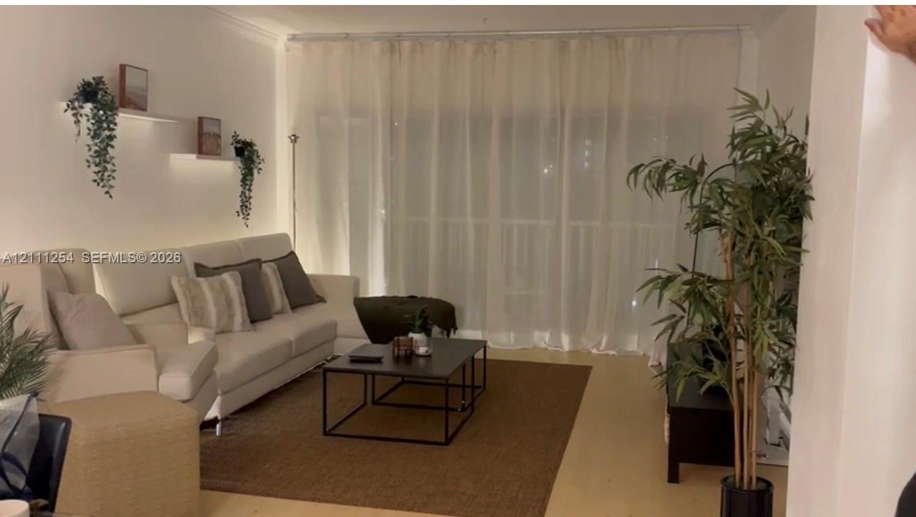 Interior space featuring light-toned flooring, wall-mounted display shelving with integrated lighting, and floor-to-ceiling window treatment Interior space featuring light-toned flooring, wall-mounted display shelving with integrated lighting, and floor-to-ceiling window treatment