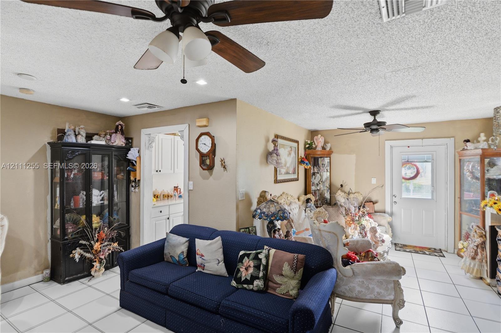 Neutral-toned interior featuring large-format ceramic tile flooring, two ceiling-mounted fans with light kits, and recessed lighting