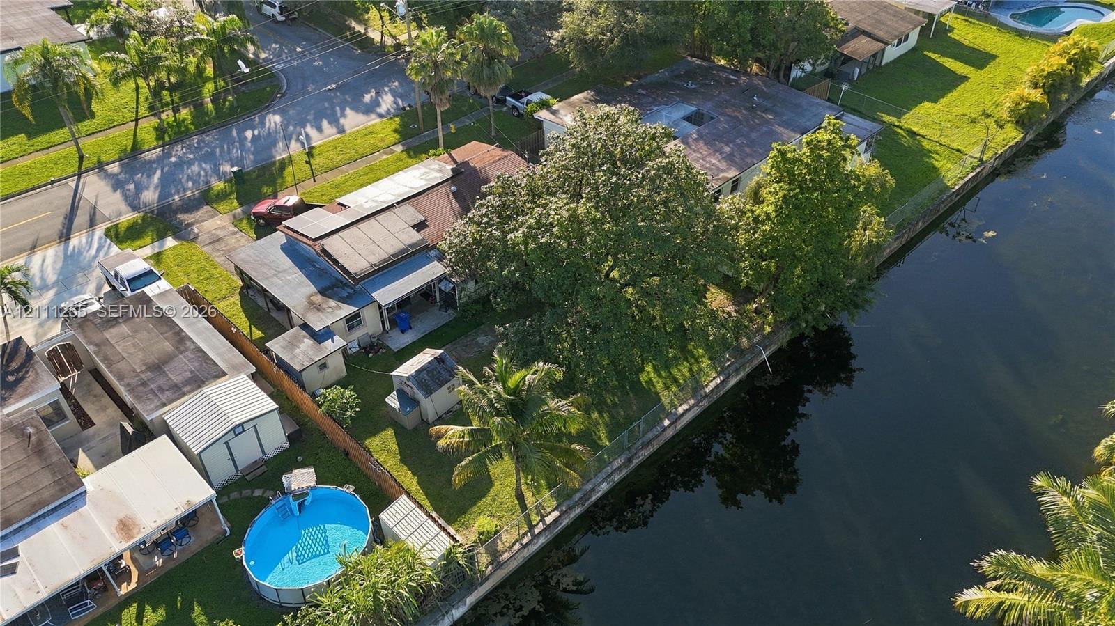 Waterfront property featuring a canal-side lot, mature trees, and a fenced perimeter