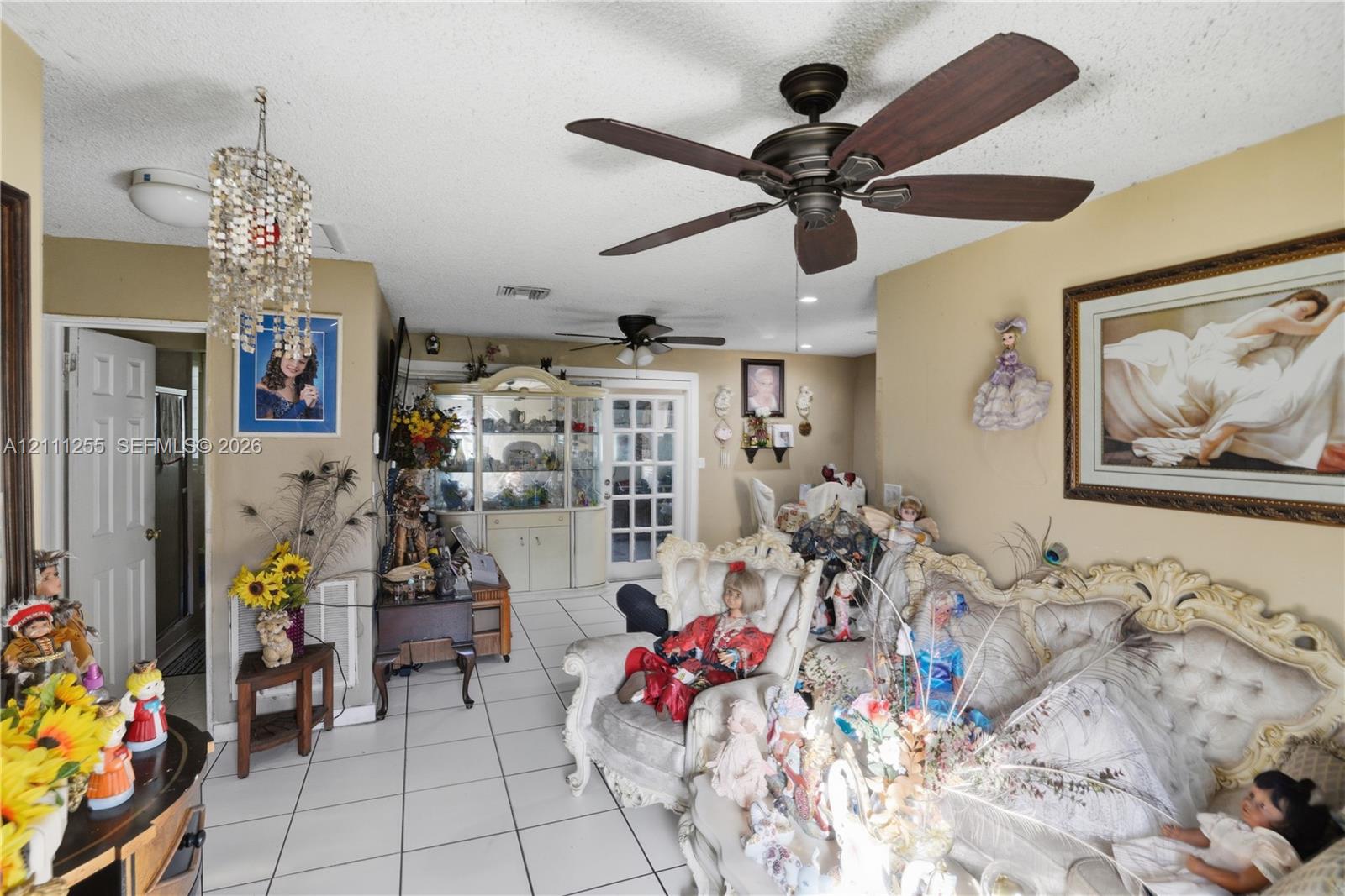 Tile flooring, built-in display cabinetry, dual ceiling fans, and a multi-pane glass entry door