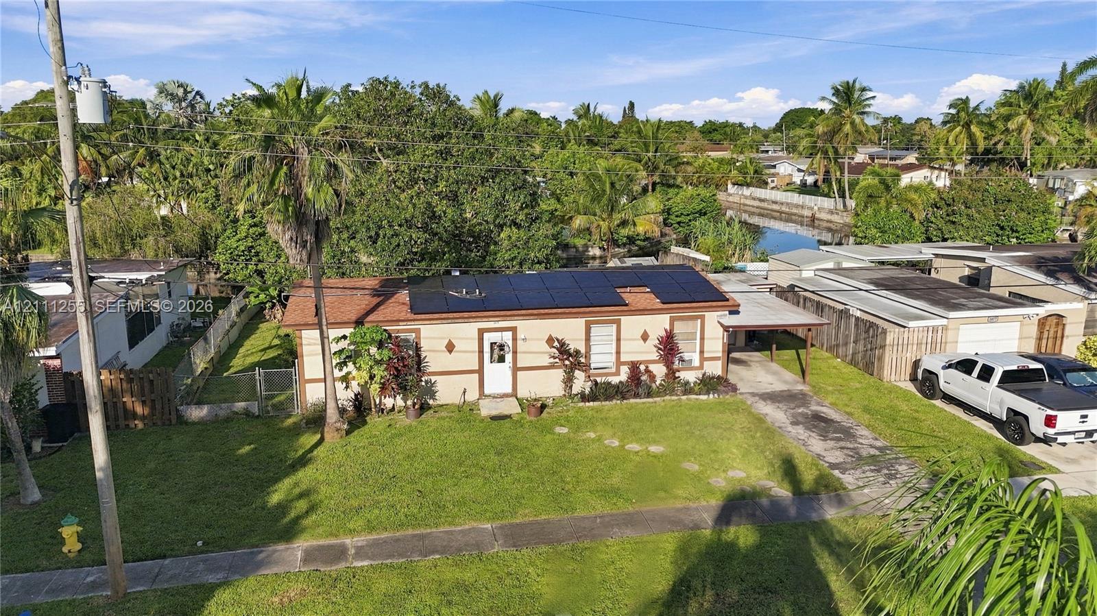 Single-story residence featuring a shingle roof equipped with solar panels, a concrete driveway with a covered carport, and exterior masonry construction