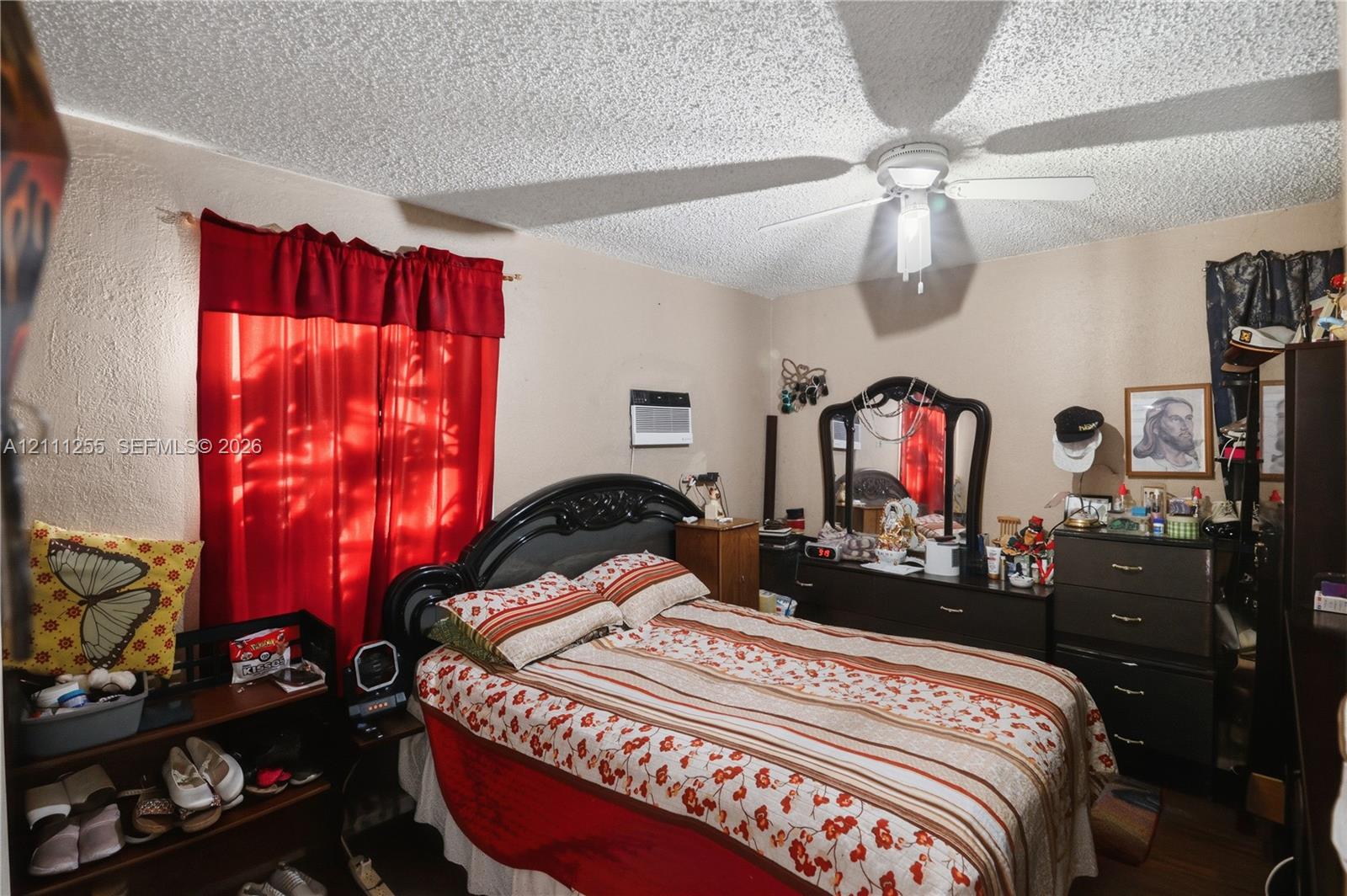 Room featuring a ceiling fan with integrated lighting, wall-mounted air conditioning unit, and textured ceiling
