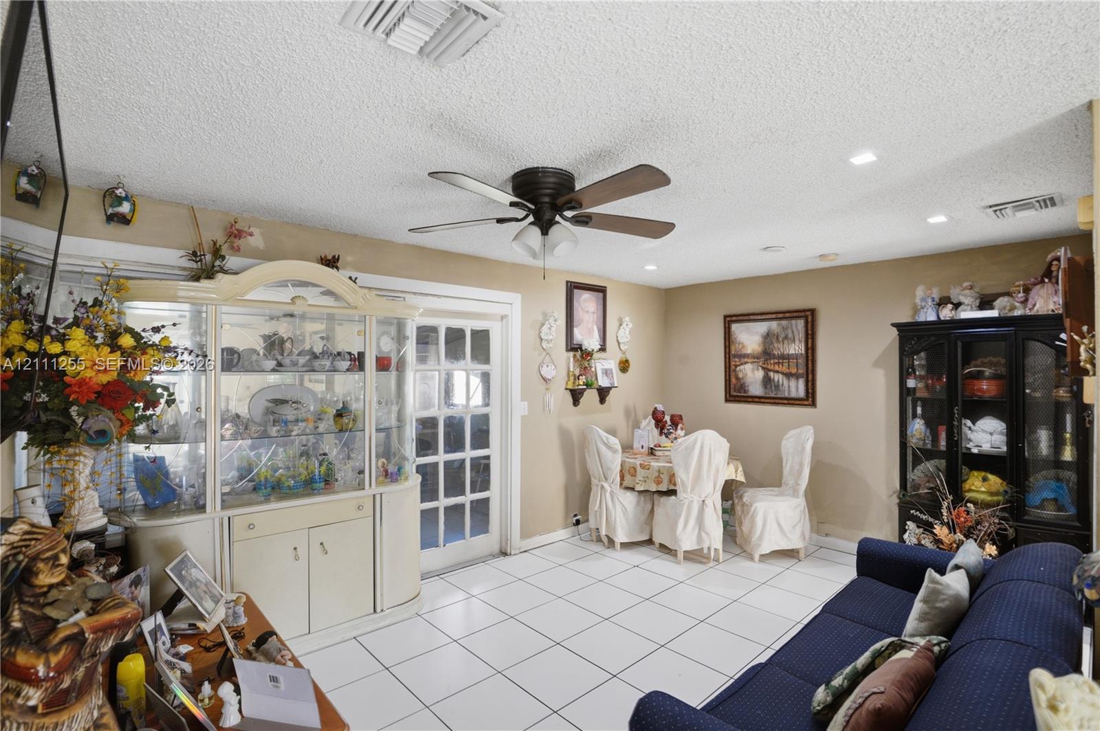 Interior space featuring white tiled flooring, recessed ceiling lighting, a dark-finish ceiling fan, and a multi-pane glass door