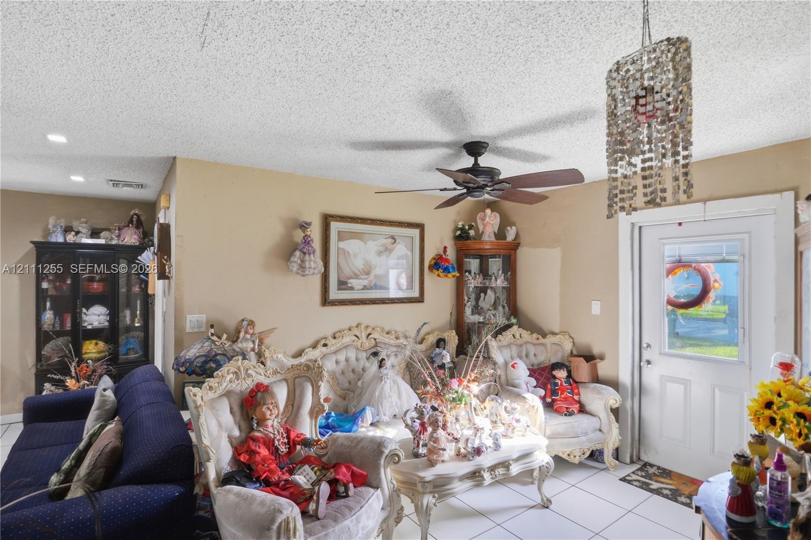 Interior space featuring a ceiling fan, textured ceiling, light-colored floor tile, and a multi-pane glass entry door