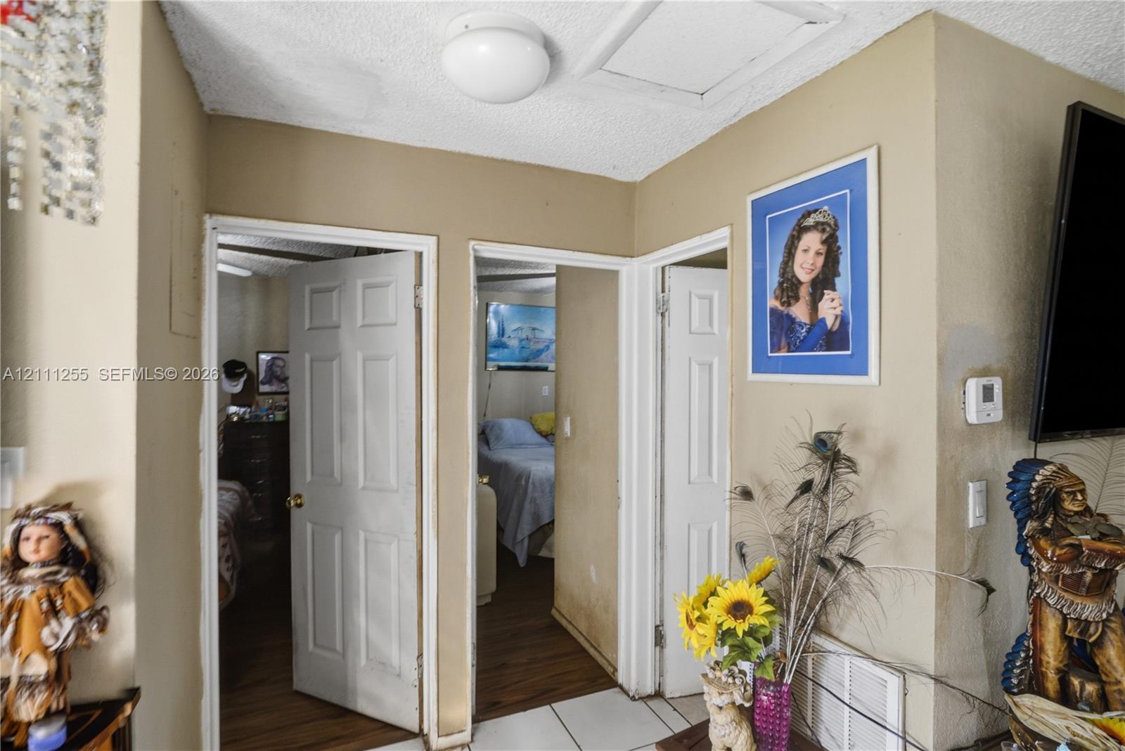 Interior space featuring six-panel doors, ceiling-mounted lighting, and a combination of white floor tile and wood-finish flooring