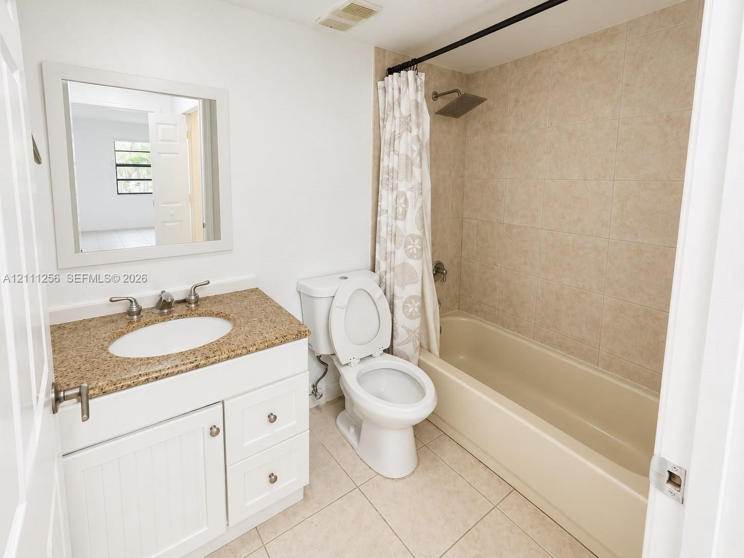 White vanity with speckled stone countertop, integrated sink, large wall-mounted mirror, ceramic tile shower surround, and square rainfall showerhead White vanity with speckled stone countertop, integrated sink, large wall-mounted mirror, ceramic tile shower surround, and square rainfall showerhead