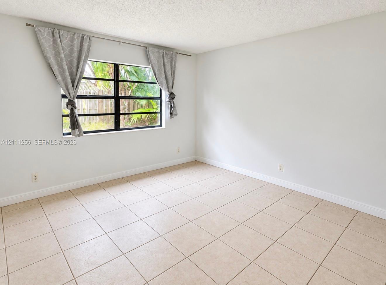 Neutral interior space featuring ceramic tile flooring, solid white walls, and a multi-pane window with a black frame Neutral interior space featuring ceramic tile flooring, solid white walls, and a multi-pane window with a black frame
