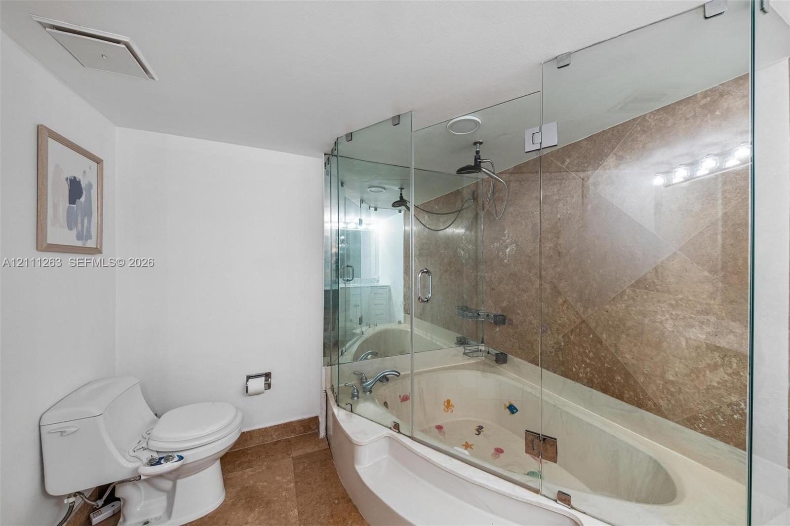 Glass-enclosed soaking tub with stone tile surround, integrated shower fixture, and ceramic floor tile