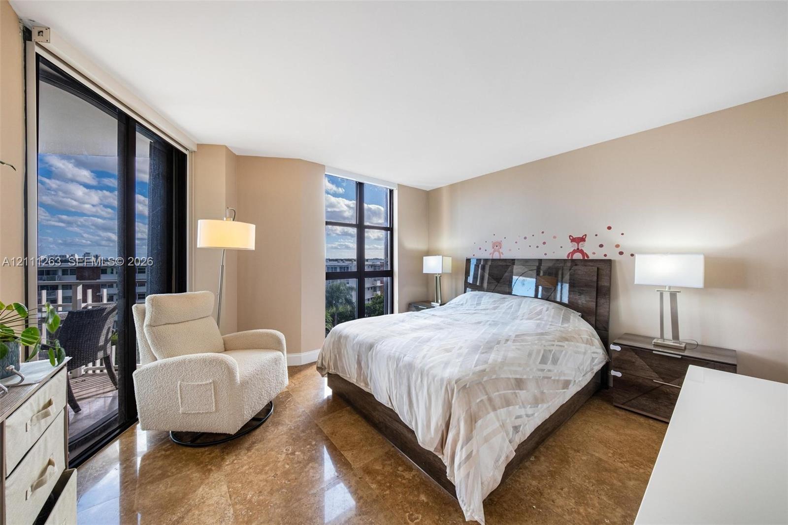 Polished stone flooring, floor-to-ceiling windows, and sliding glass doors opening to a balcony