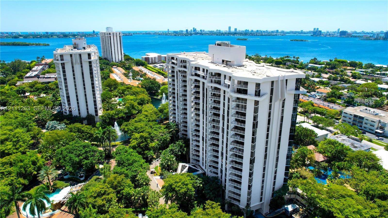 High-rise condominium featuring private balconies, lush grounds, mature landscaping, and swimming pools