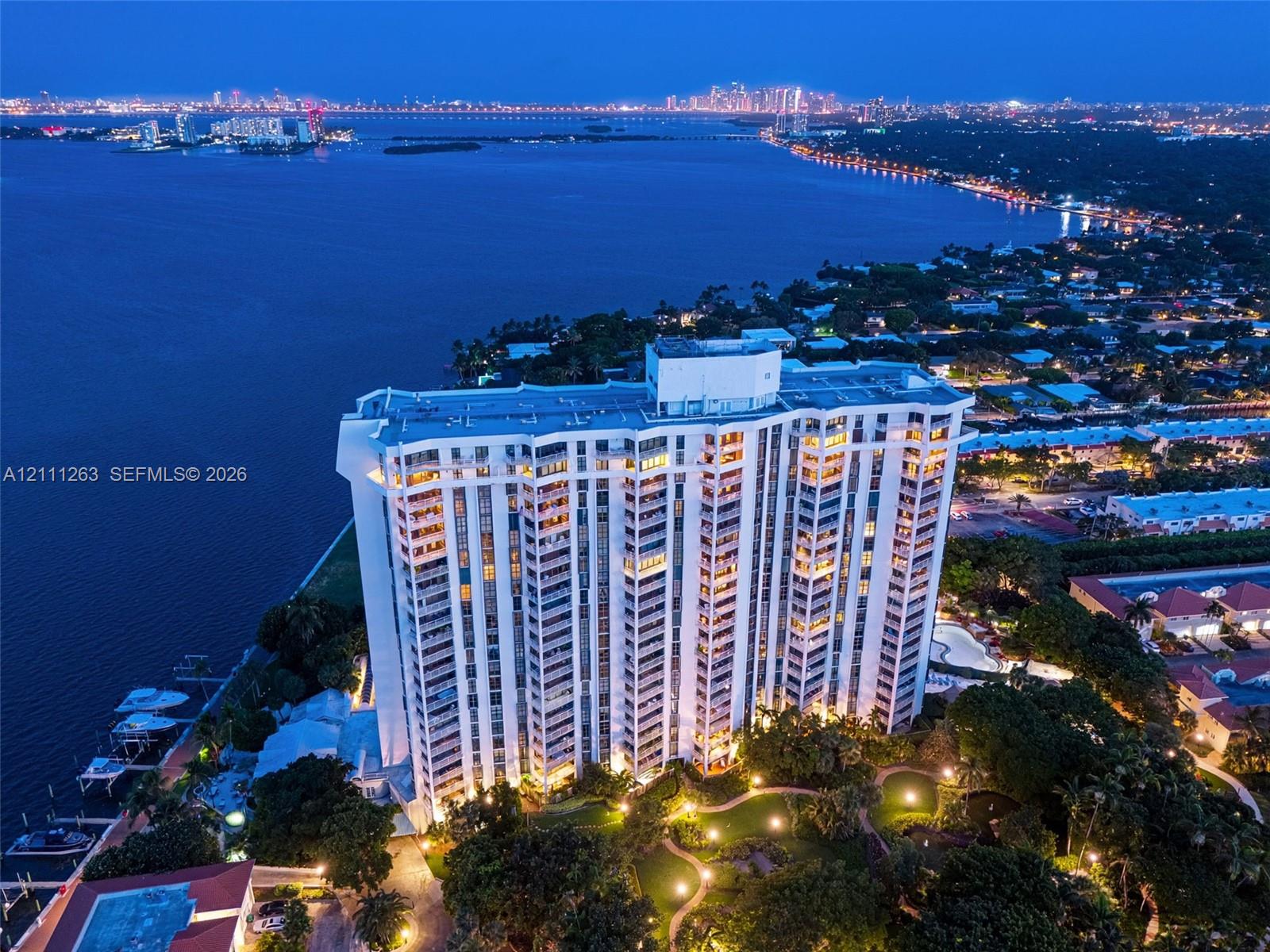 High-rise building featuring private boat slips, landscaped grounds, a paved walking path, and waterfront positioning