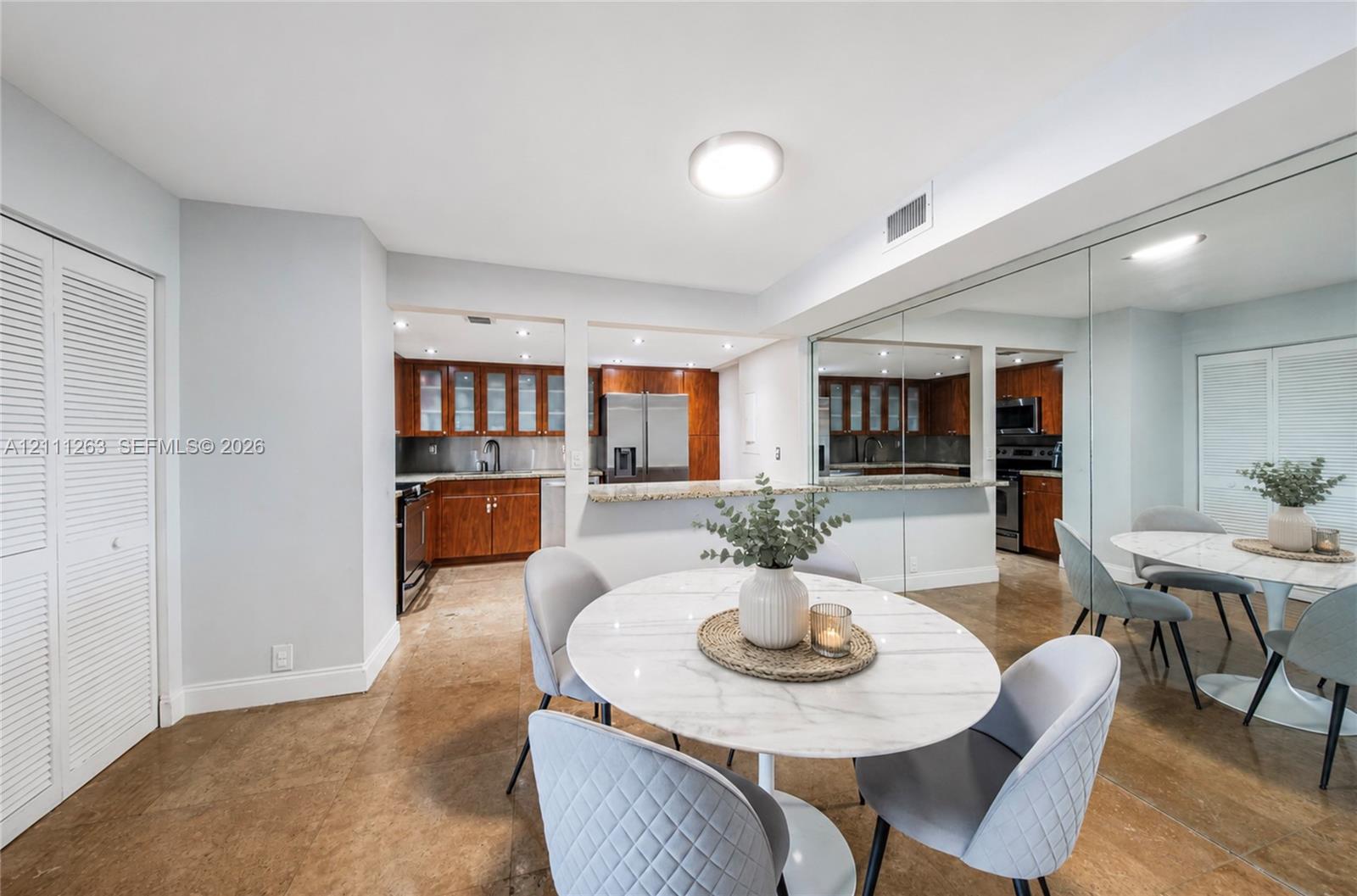 Kitchen featuring wood cabinetry, stone countertops, a breakfast bar, and large wall-mounted mirrors