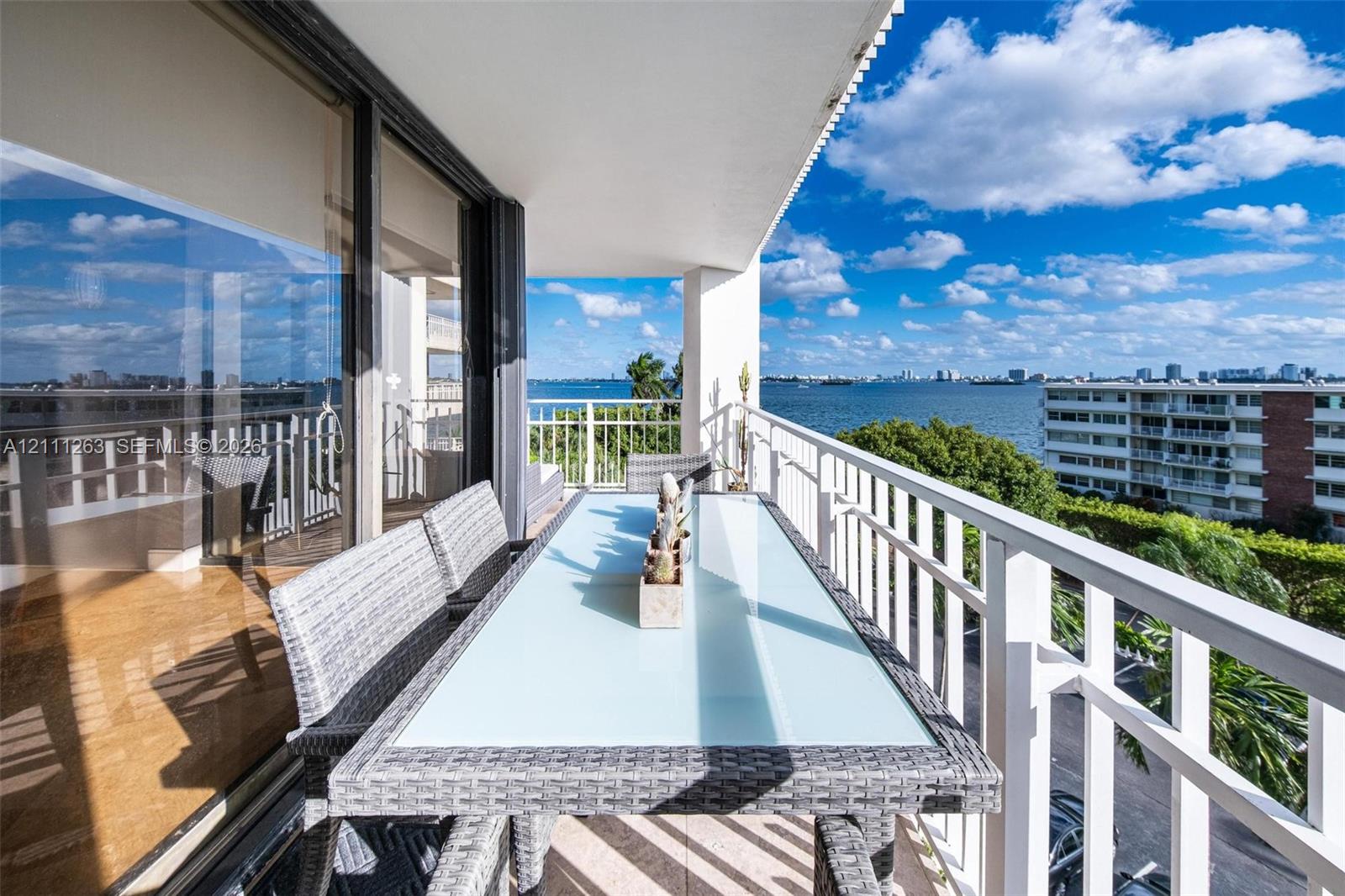 Covered balcony featuring white metal railings, tile flooring, and floor-to-ceiling glass sliding doors