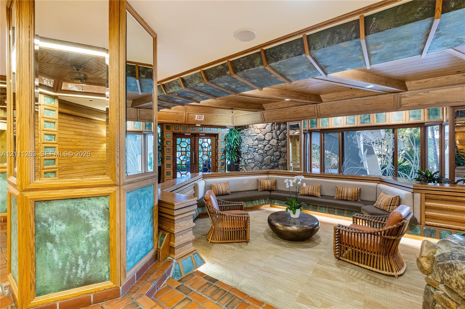 Custom architectural interior featuring natural wood-finish beams, stacked stone accent walls, patterned glass paneling, terracotta-tone tile flooring, and integrated built-in seating