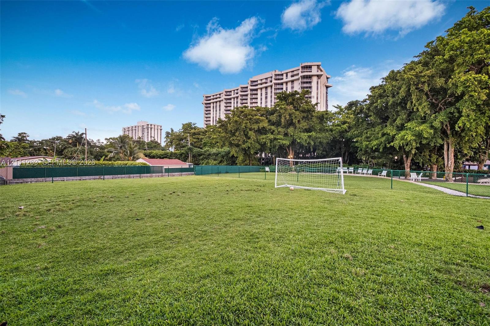 Expansive grass field featuring a perimeter fence and a built-in soccer goal