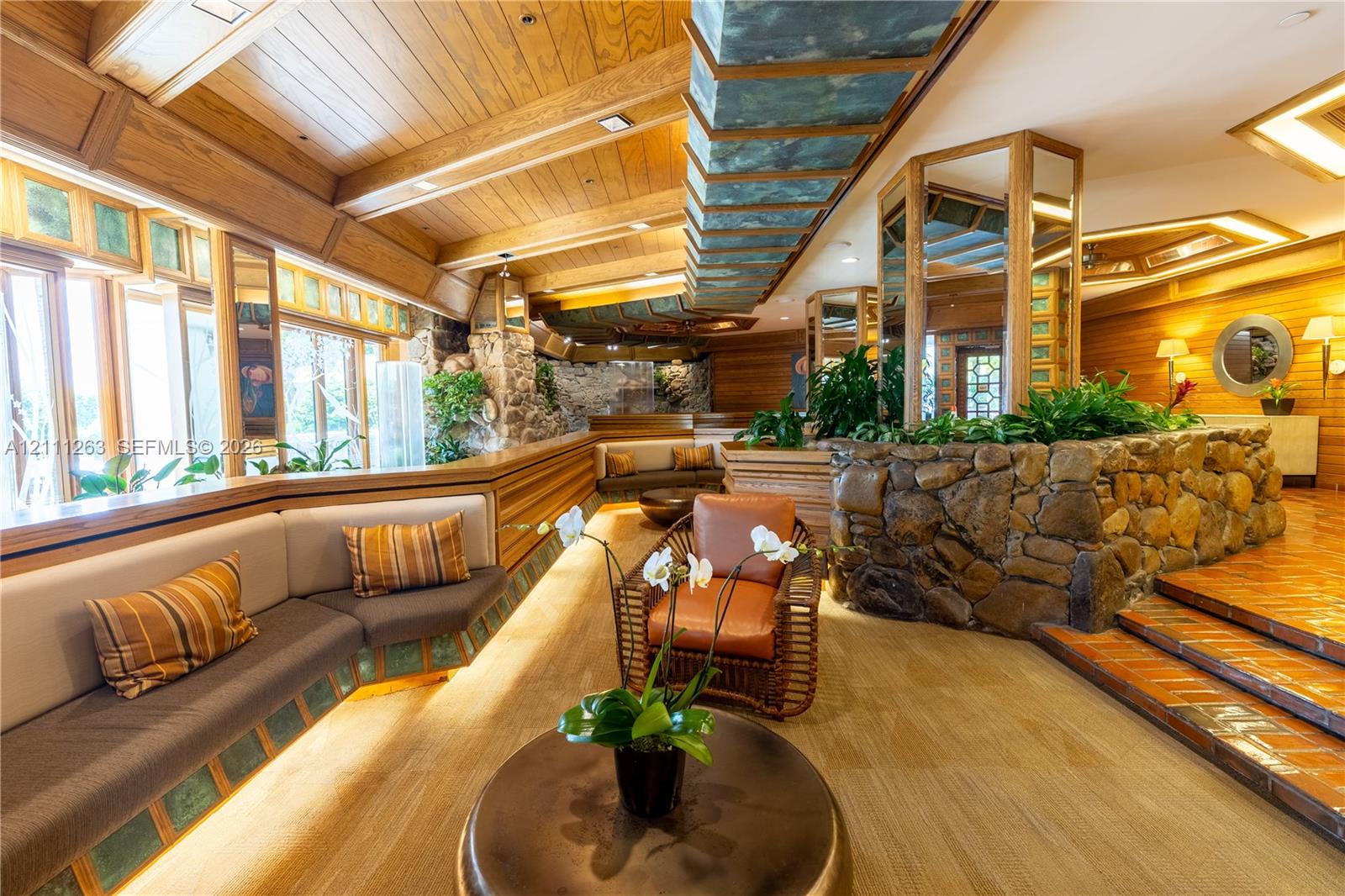 Vaulted wood-paneled ceiling, integrated stone masonry walls, built-in recessed seating, and terra-cotta tile flooring