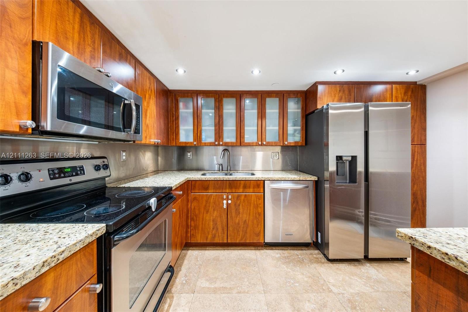 Kitchen featuring wood cabinetry, stone countertops, stainless steel appliances, glass-front upper cabinets, and recessed lighting