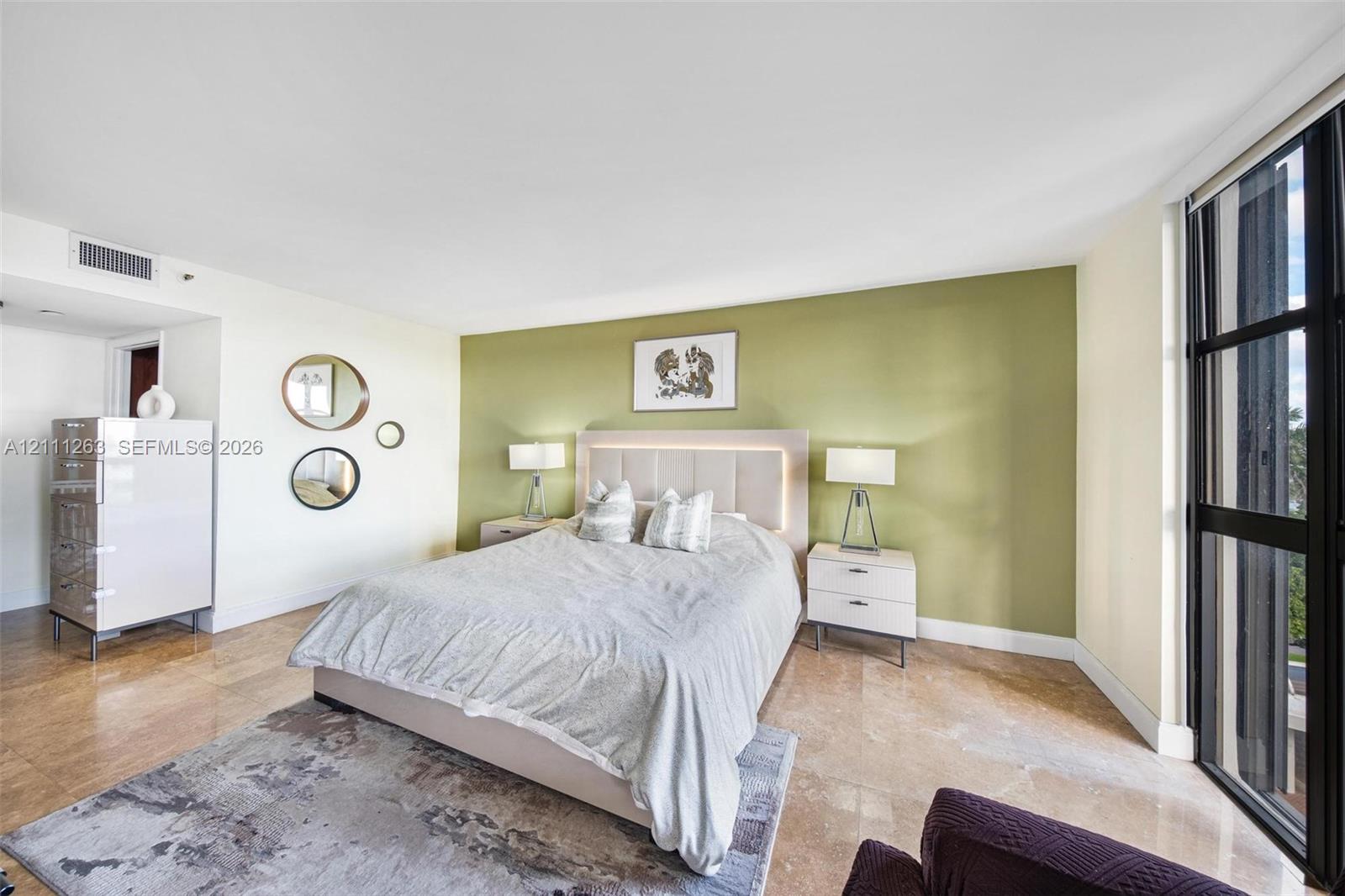 Floor-to-ceiling windows with black metal frames, stone flooring, and an accent wall