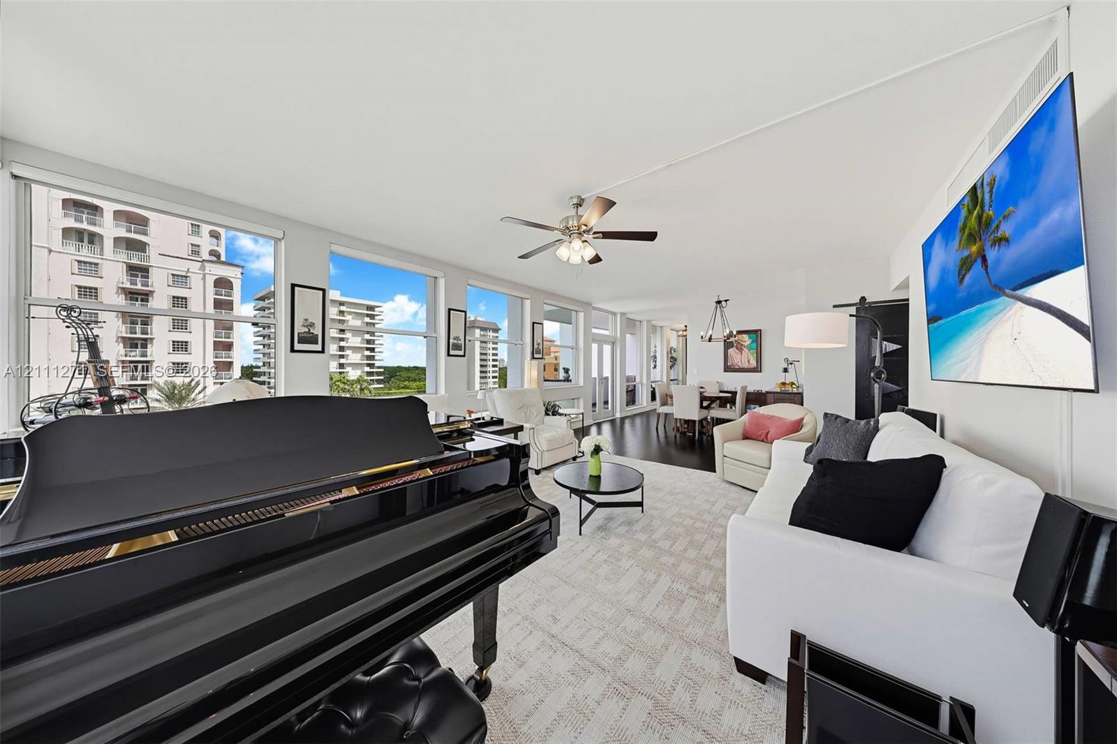 Open-concept interior featuring oversized windows, wood-finish flooring, and a ceiling fan with integrated lighting Open-concept interior featuring oversized windows, wood-finish flooring, and a ceiling fan with integrated lighting