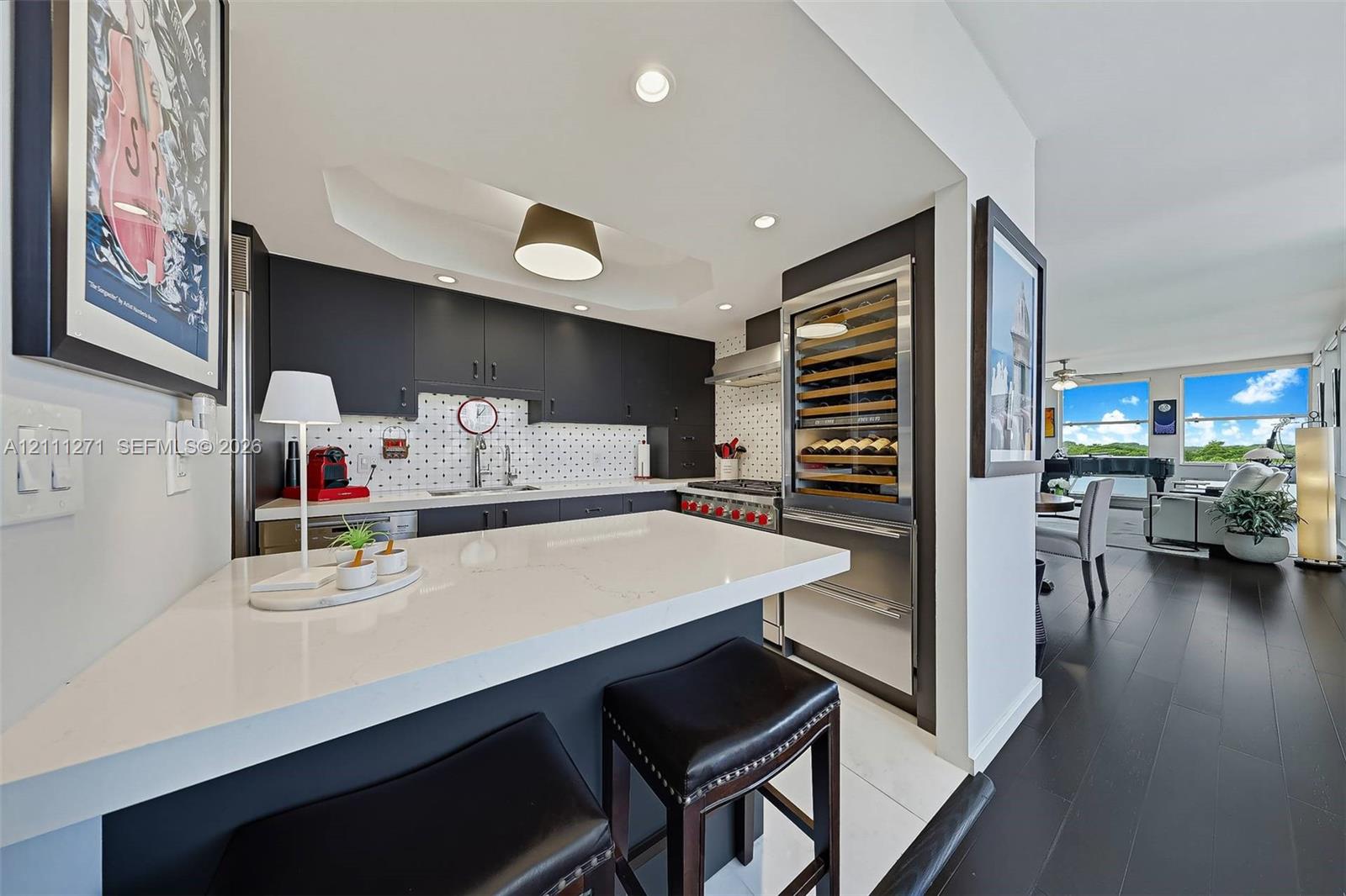 Kitchen featuring dark cabinetry, solid-surface breakfast bar, mosaic tile backsplash, stainless steel range, and built-in wine refrigeration Kitchen featuring dark cabinetry, solid-surface breakfast bar, mosaic tile backsplash, stainless steel range, and built-in wine refrigeration