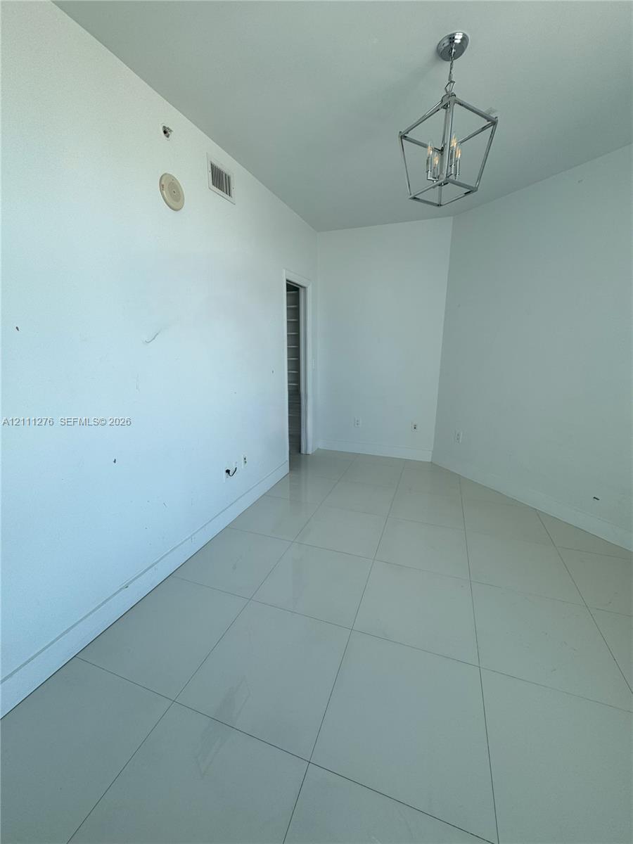 Room featuring large-format ceramic tile flooring and an industrial-style metal geometric chandelier