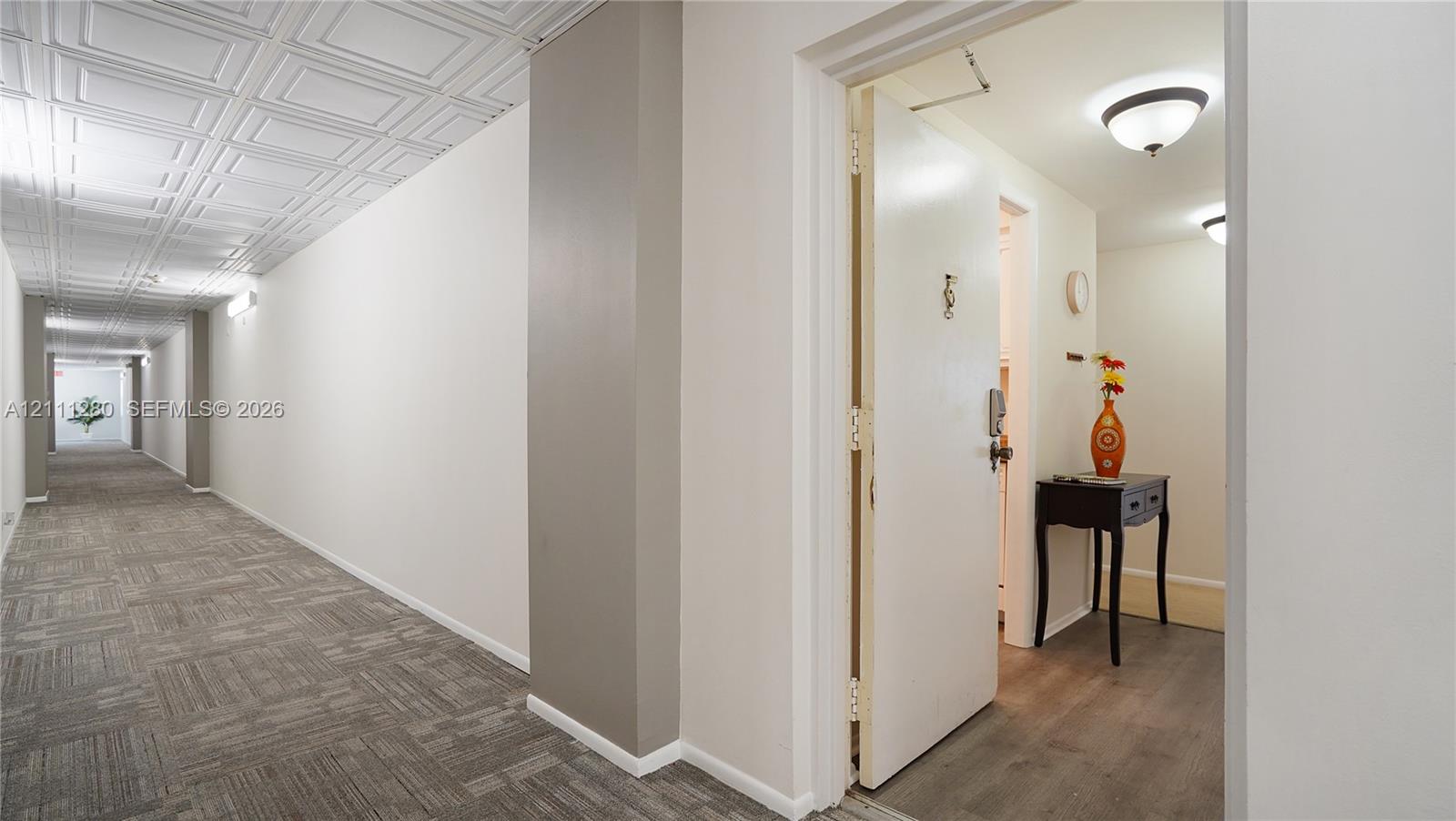 Hallway featuring coffered ceiling panels, neutral wall finishes, carpeted flooring, and recessed dome lighting