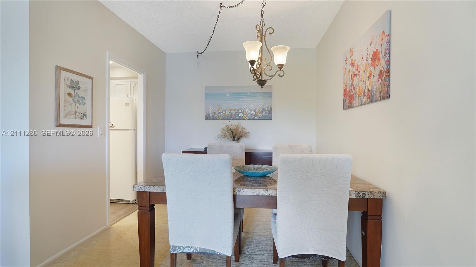 Dining area featuring a three-arm chandelier with frosted glass shades and neutral wall finishes