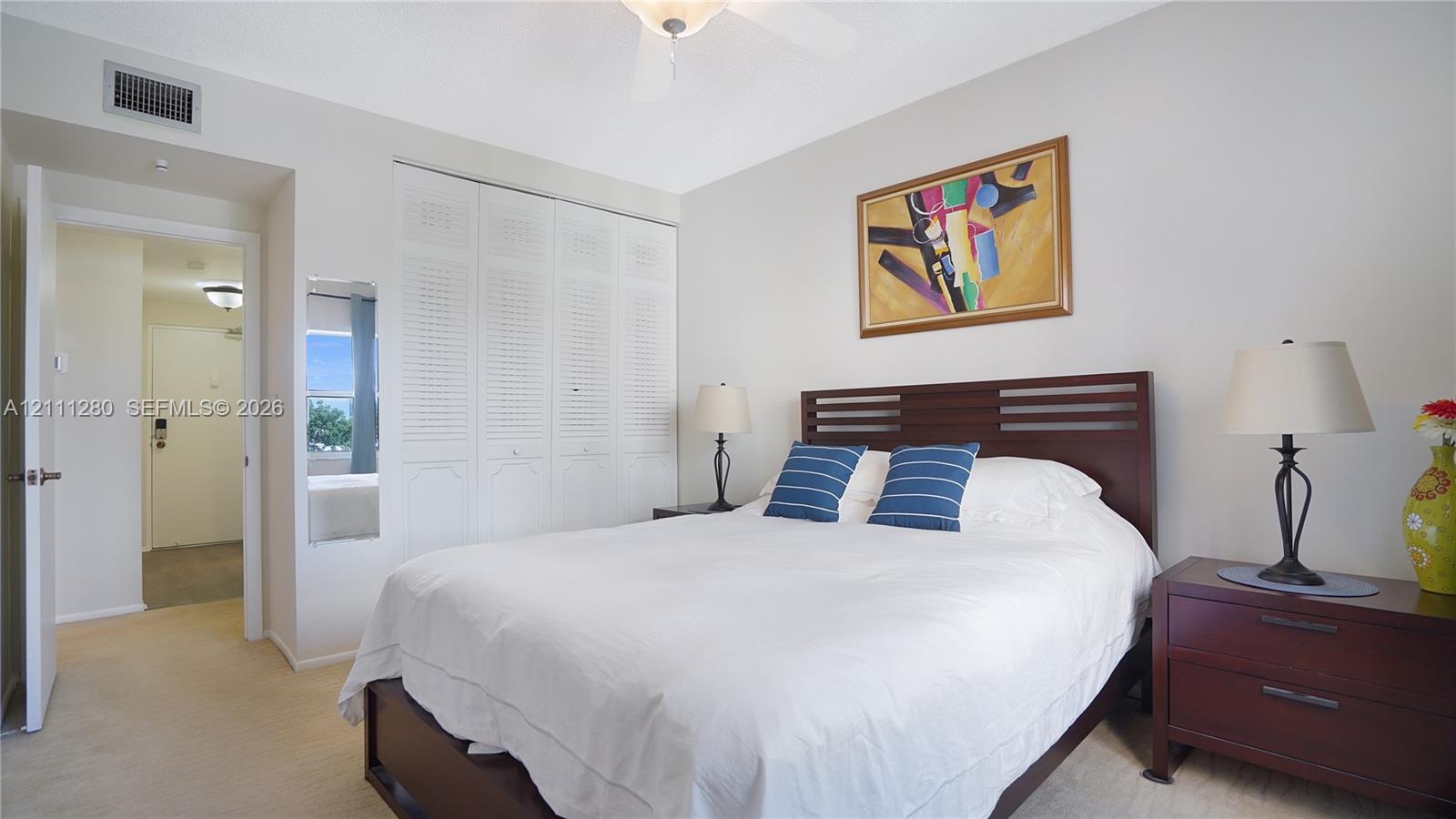 Interior space featuring wall-to-wall carpeting, floor-to-ceiling louvered closet doors, and a ceiling fan with integrated lighting