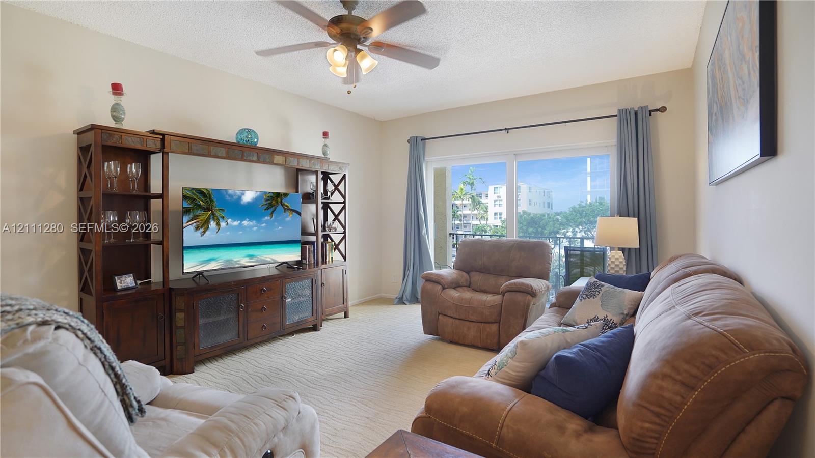 Living space featuring a ceiling fan with integrated lighting and sliding glass doors providing external access