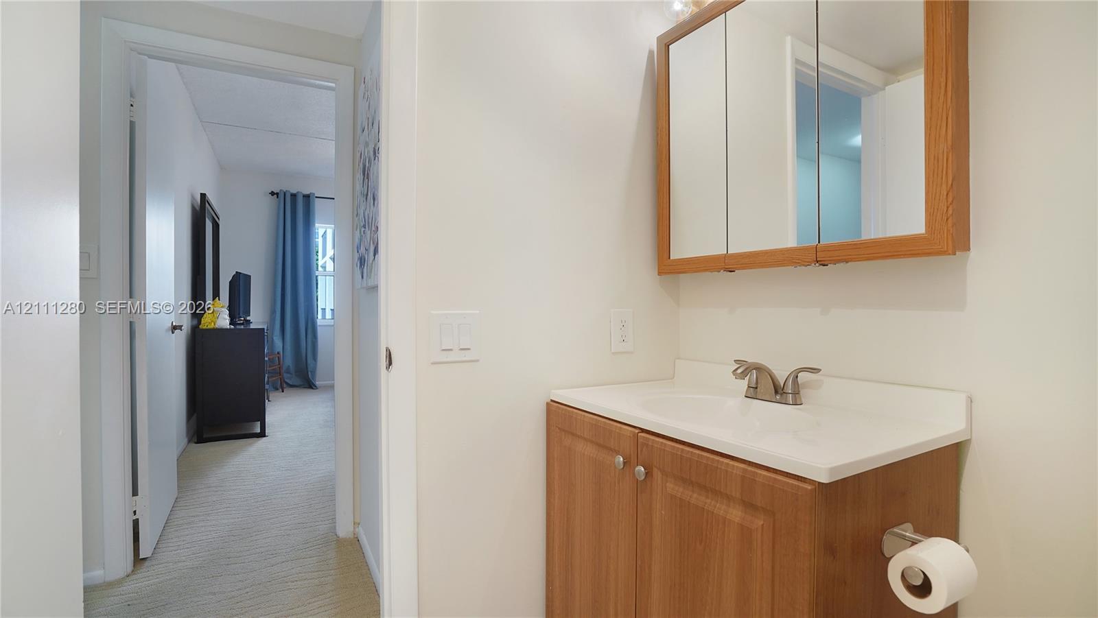 Wood-finish vanity cabinet, integrated countertop with basin, dual-handle faucet, and wooden-framed mirrored medicine cabinet