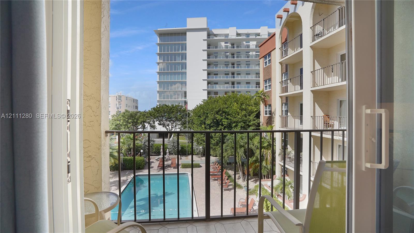 Balcony with metal railing overlooking an in-ground swimming pool and landscaped grounds