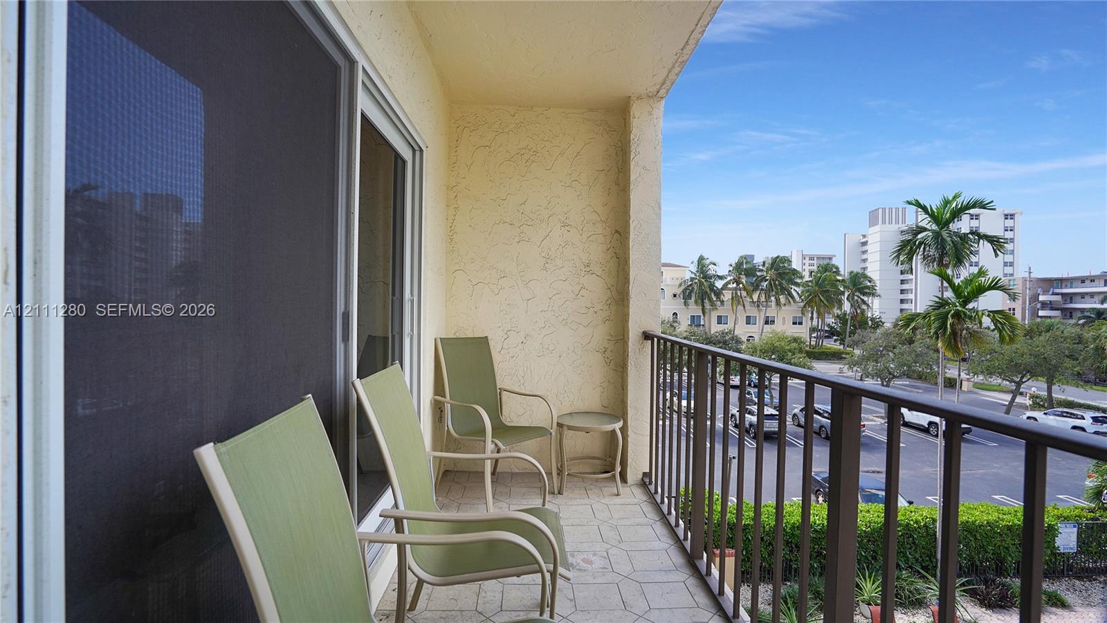 Covered balcony featuring a textured stucco wall, tile flooring, and metal railing