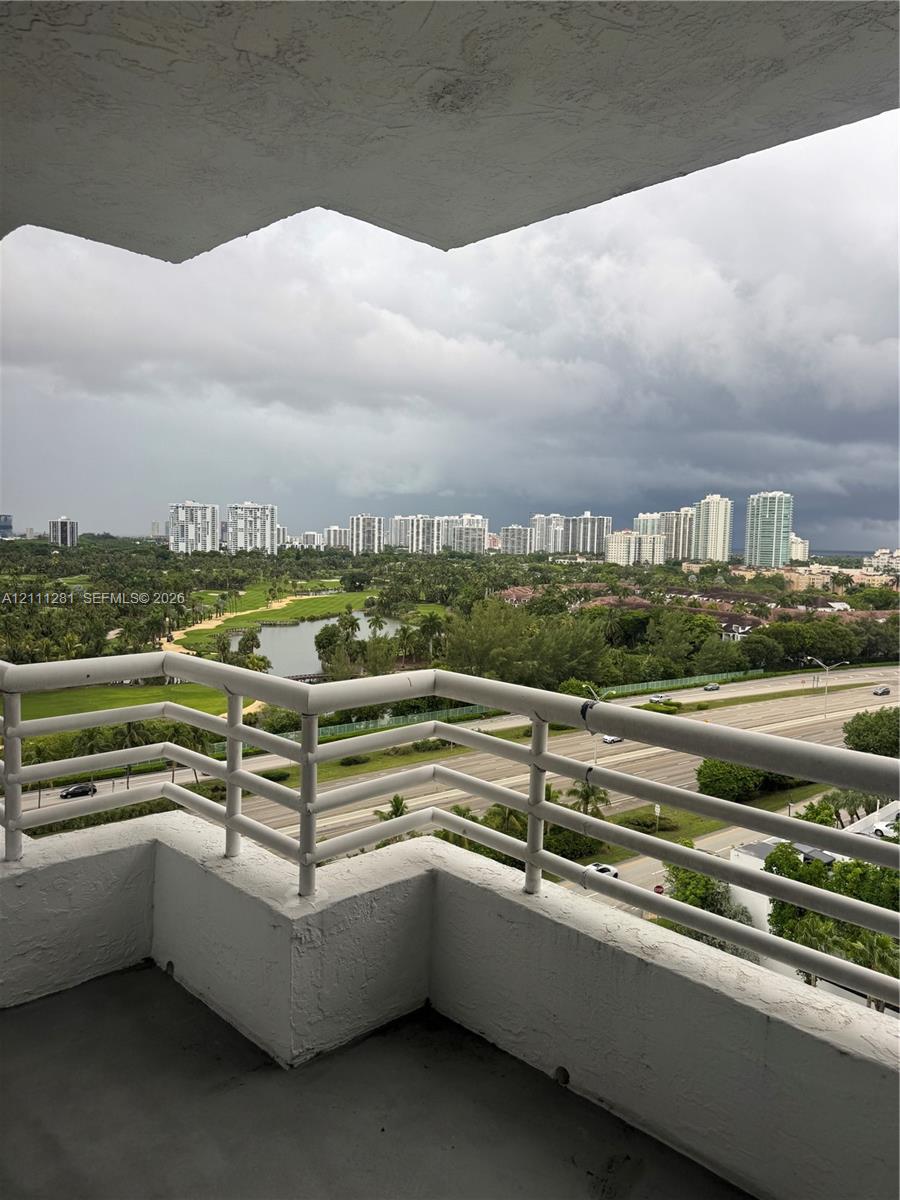 Covered balcony featuring white metal railings and concrete flooring Covered balcony featuring white metal railings and concrete flooring