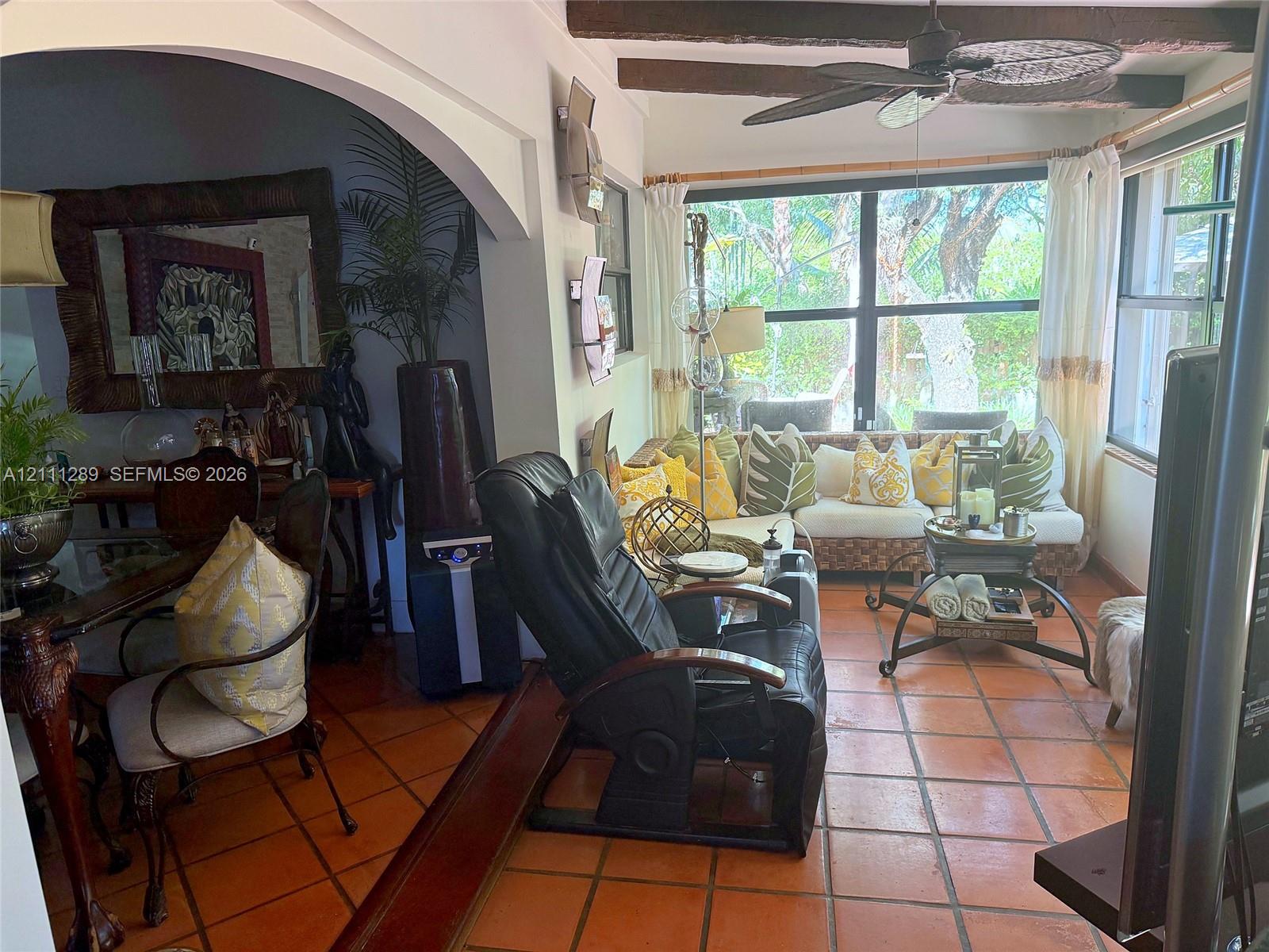 Sunroom featuring terracotta tile flooring, exposed wood ceiling beams, a ceiling fan, and large windows Sunroom featuring terracotta tile flooring, exposed wood ceiling beams, a ceiling fan, and large windows
