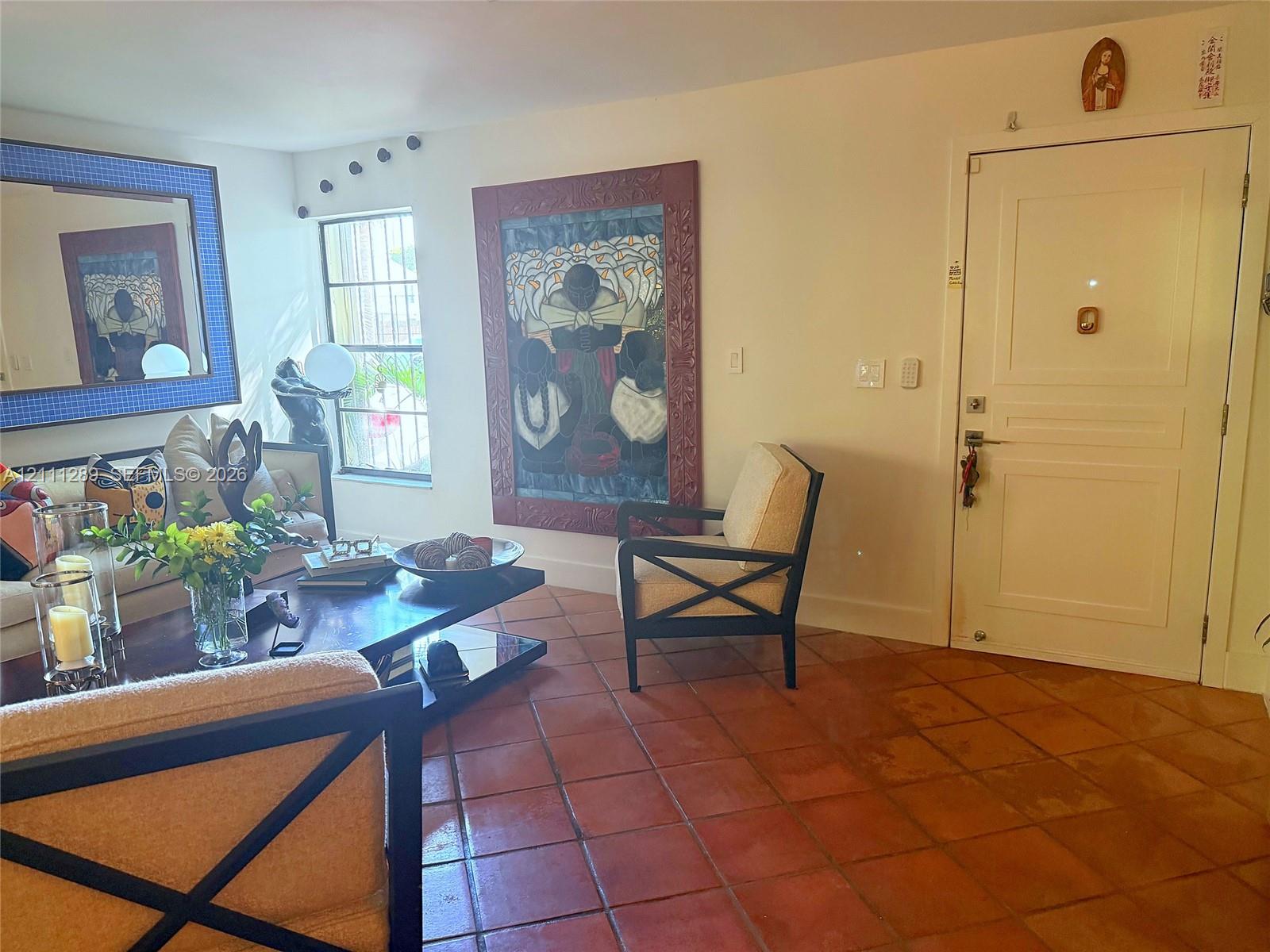 Terracotta tile flooring, multi-pane window with security bars, and solid-core paneled entry door Terracotta tile flooring, multi-pane window with security bars, and solid-core paneled entry door
